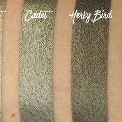 Hand applying army green shimmer eyeshadow with fingertip, showcasing pigmented payoff on skin