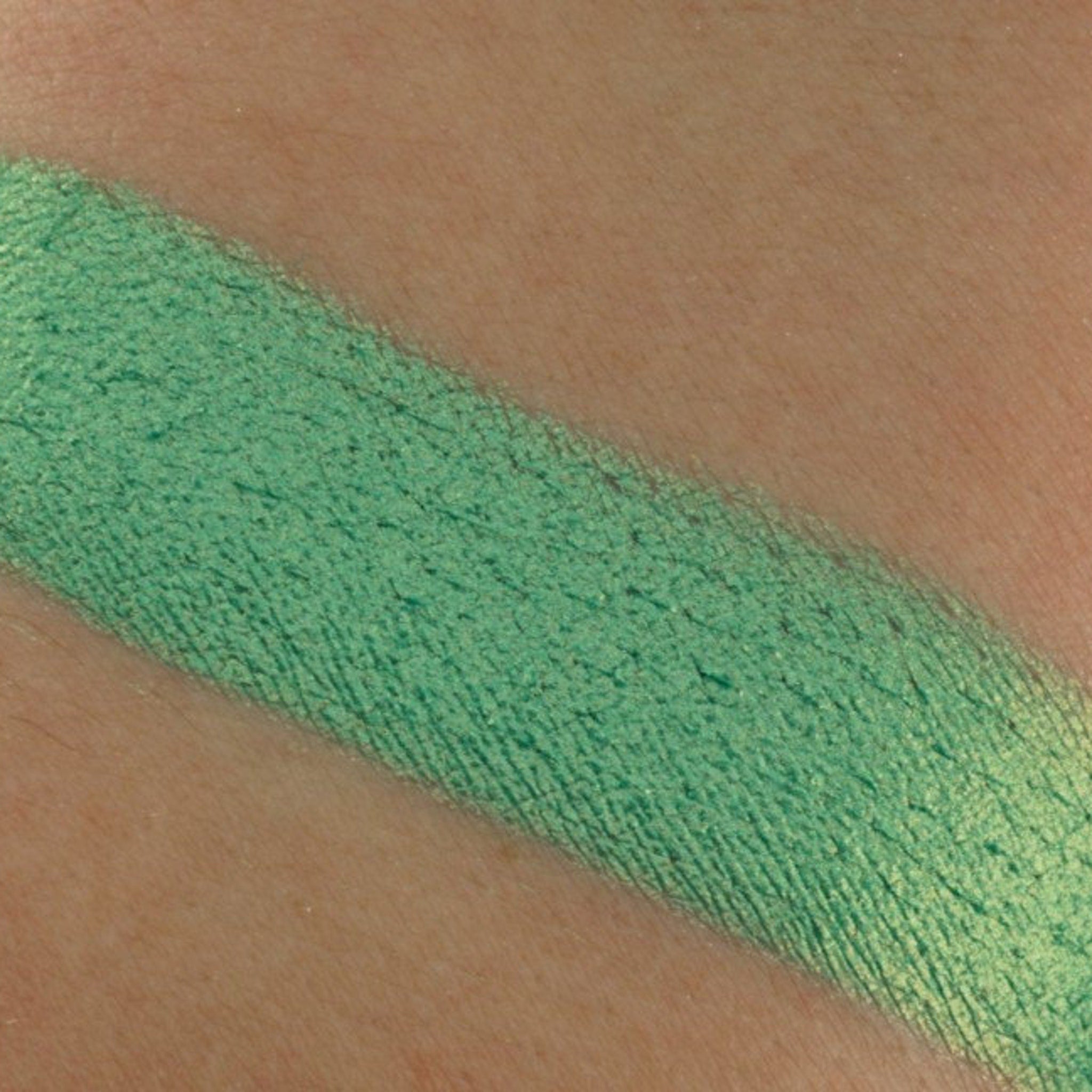 Close-up of shimmering green and blue chrome pressed pigments with metallic finish in compact duo pan
