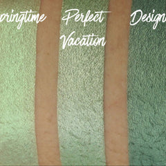 Hand applying shimmering green and blue chrome eye shadow duo with fingertip for bold metallic look