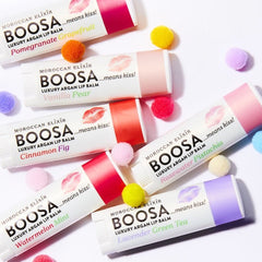 Lip balms, white tubes with colored accents, BOOSA brand text, pom-poms around them