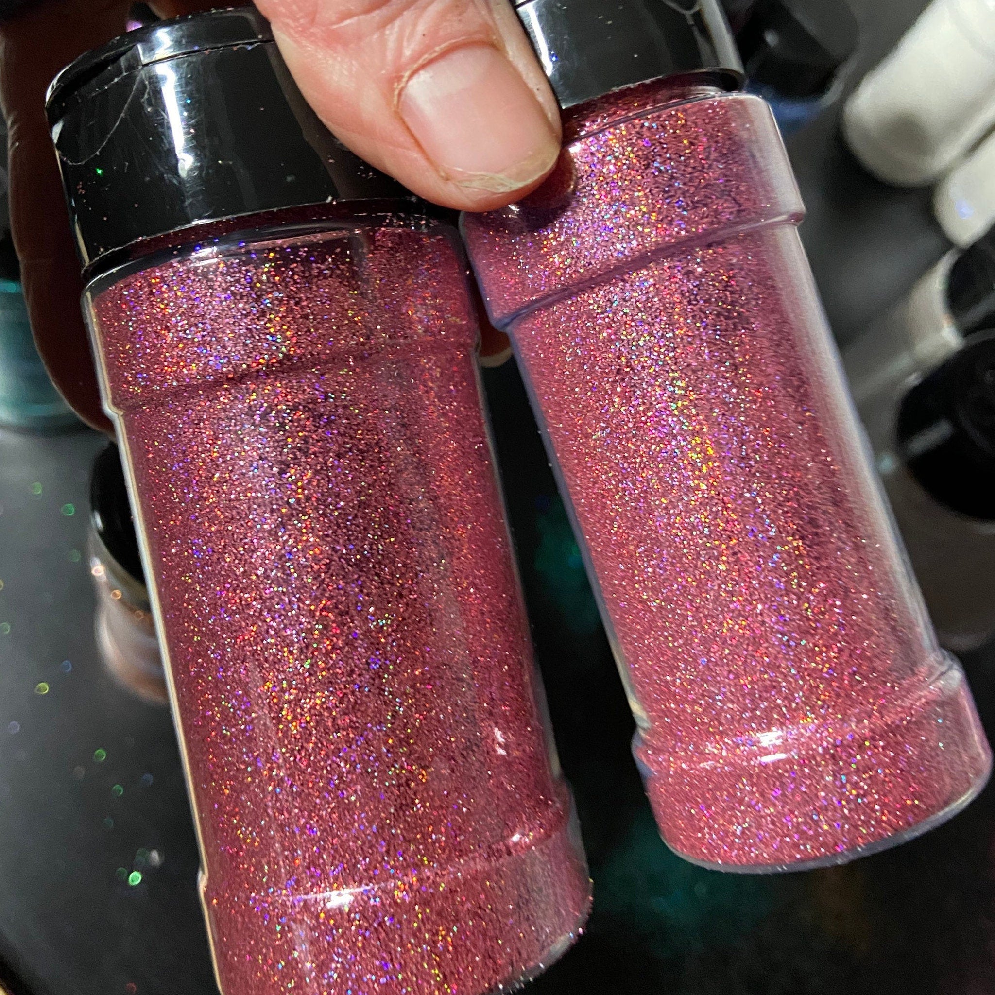 Open compact displaying holographic pink glitter eyeshadow with mirror and applicator brush