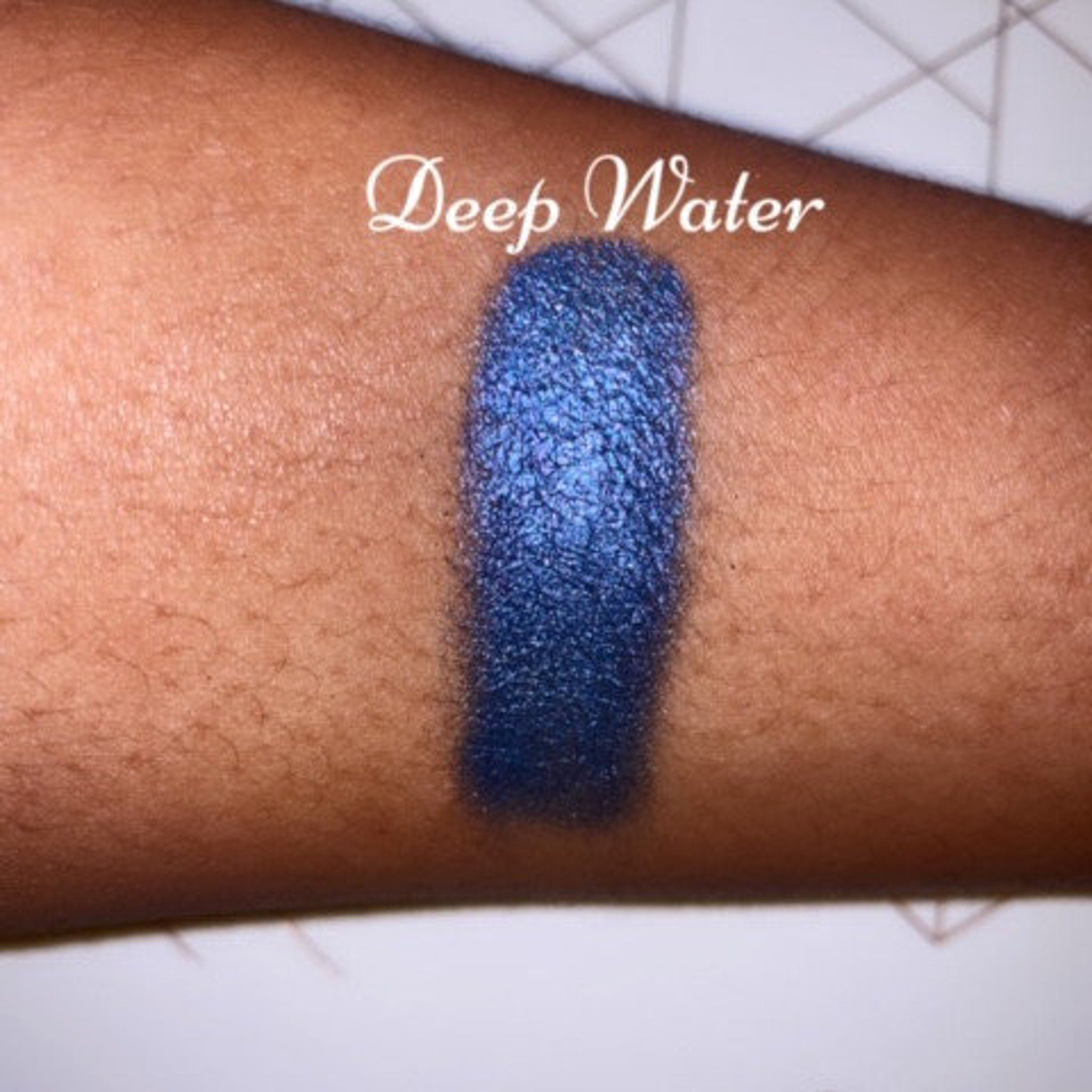 Side view of vegan shimmer eye shadow pot in deep blue shade with reflective metallic finish