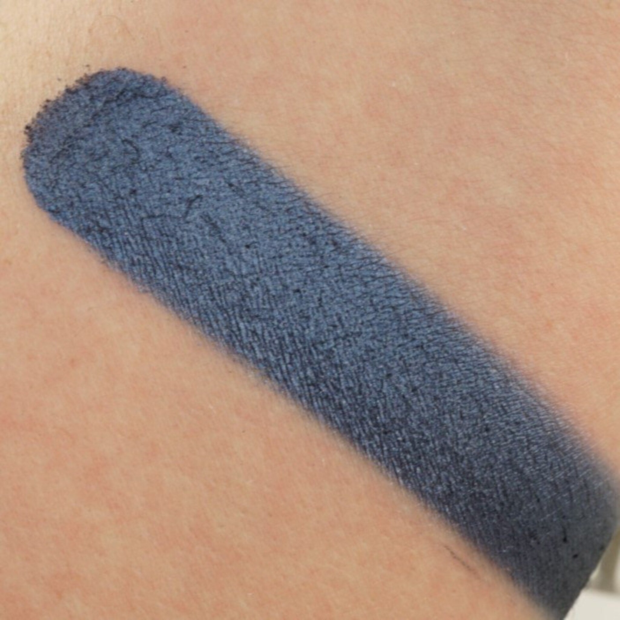 Close-up of vegan shimmer eye shadow in deep blue with sparkling flecks, showcasing smooth creamy texture