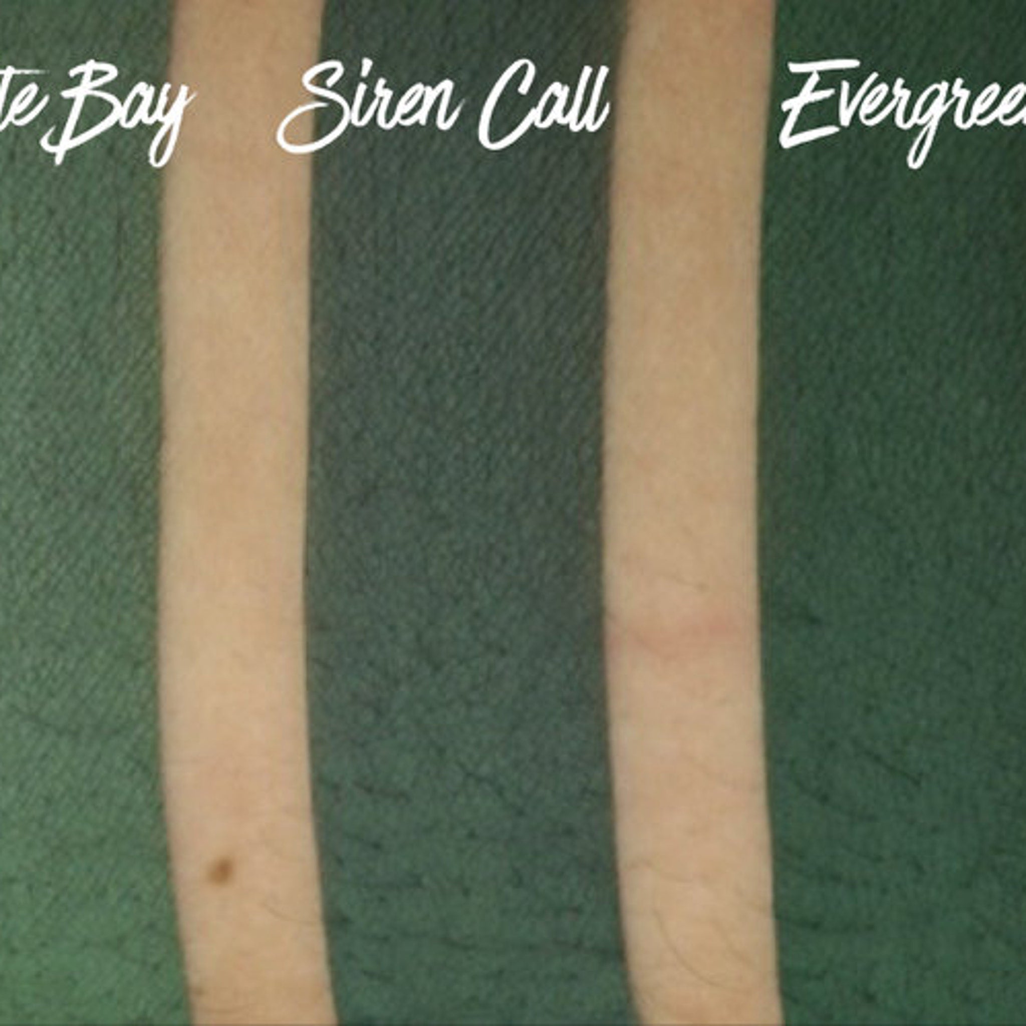 Hand applying matte evergreen eyeshadow with fingertip onto eyelid for smooth, long-lasting color payoff