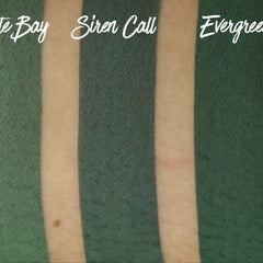 Hand applying matte evergreen eyeshadow with fingertip onto eyelid for smooth, long-lasting color payoff