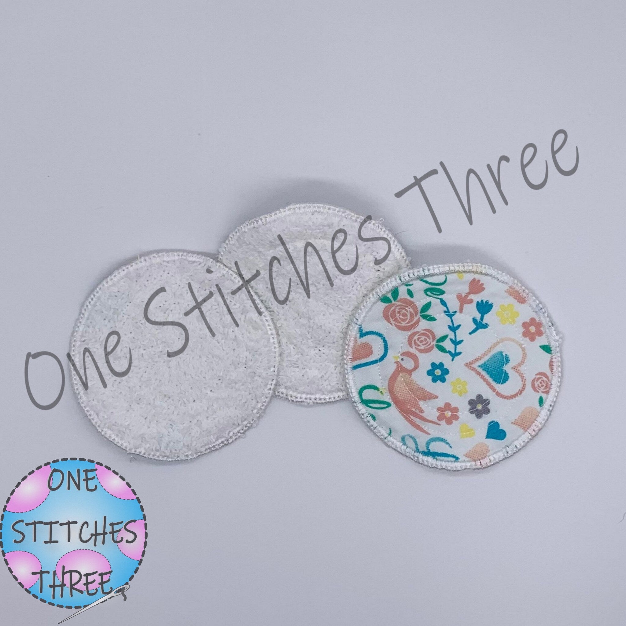 Reusable nursing pads, white terry cloth, floral print, One Stitches Three brand name visible