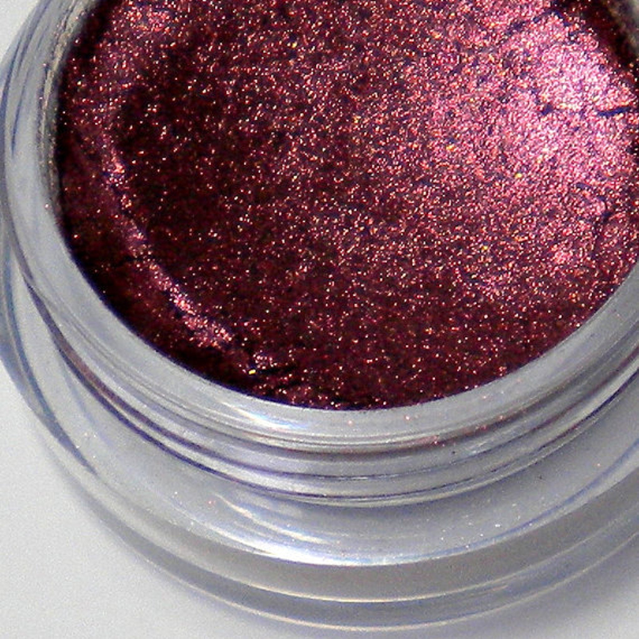 Close-up of two mineral vegan eyeshadow shades in round 5g jars with matte black lids