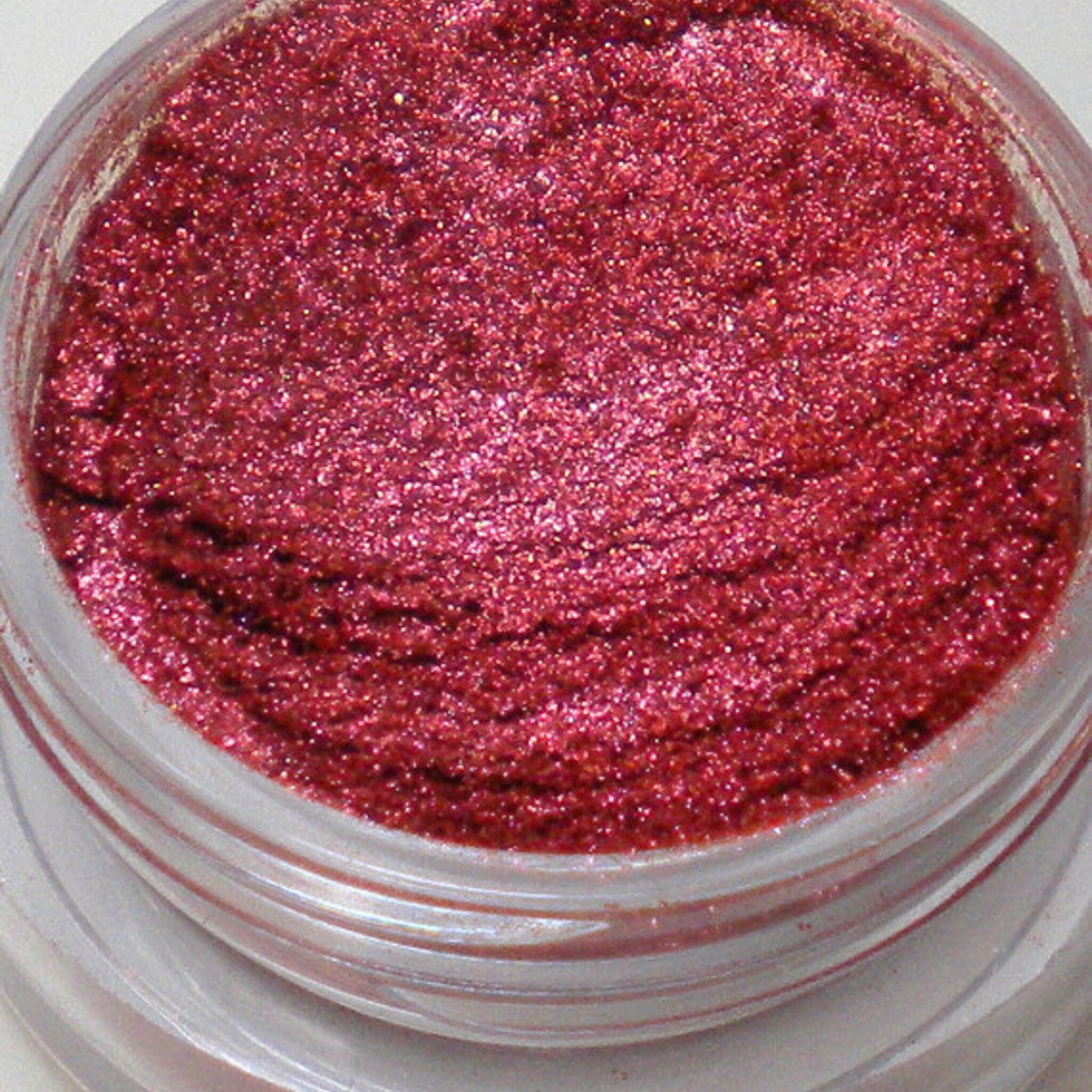 Two 5g glass jars of vegan mineral eyeshadow displayed on a marble surface with lids open showing pressed powder shades.