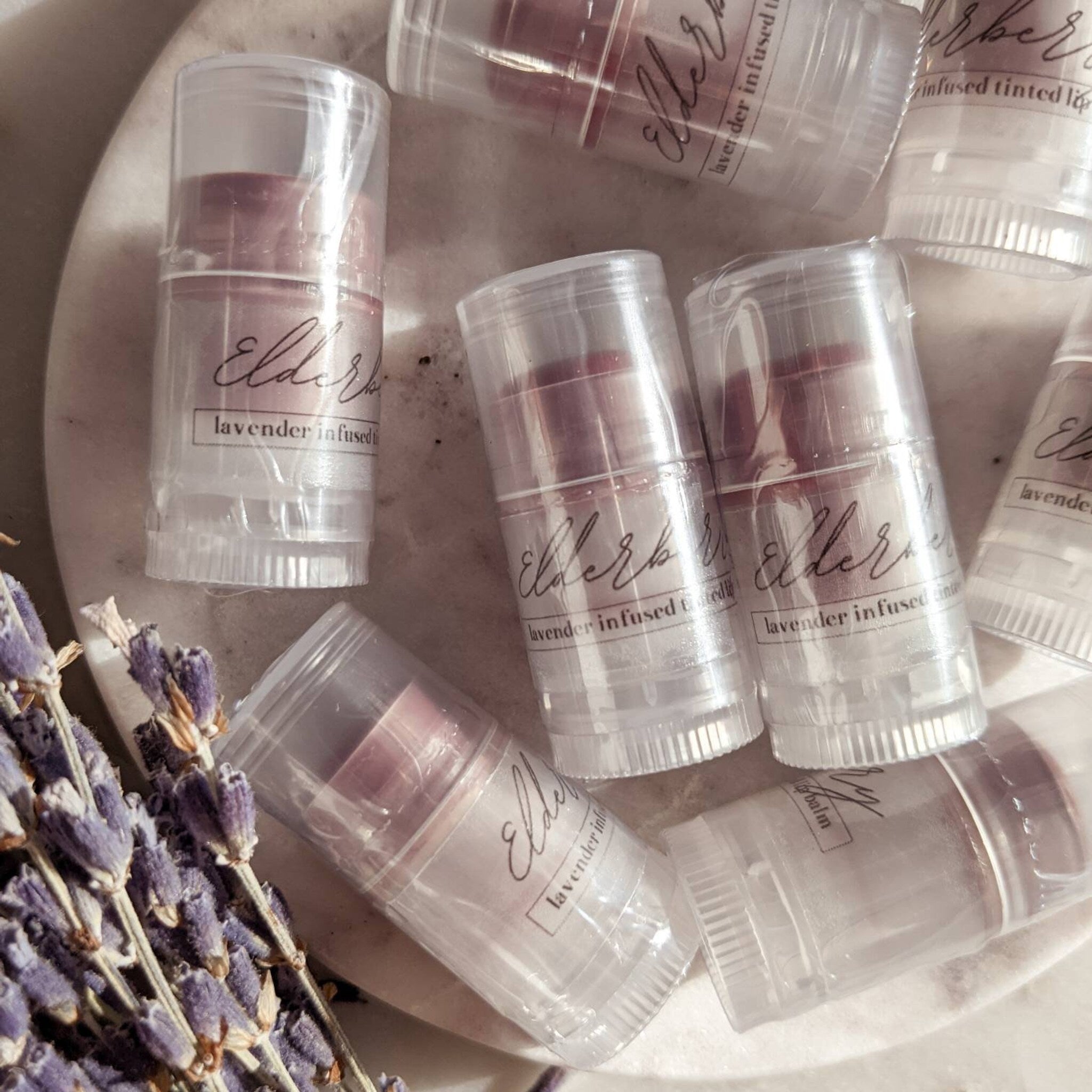Lip balm tubes, clear plastic, lavender-tinted balm, with "Elders" label and lavender sprig in background