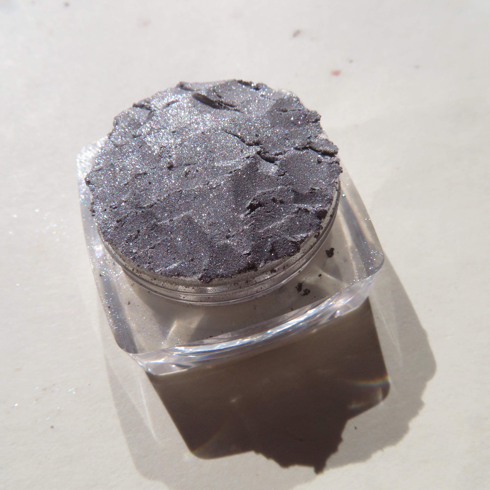 Close-up of shimmery silver chrome loose pigment eyeshadow with reflective metallic particles in a vegan eco-friendly jar