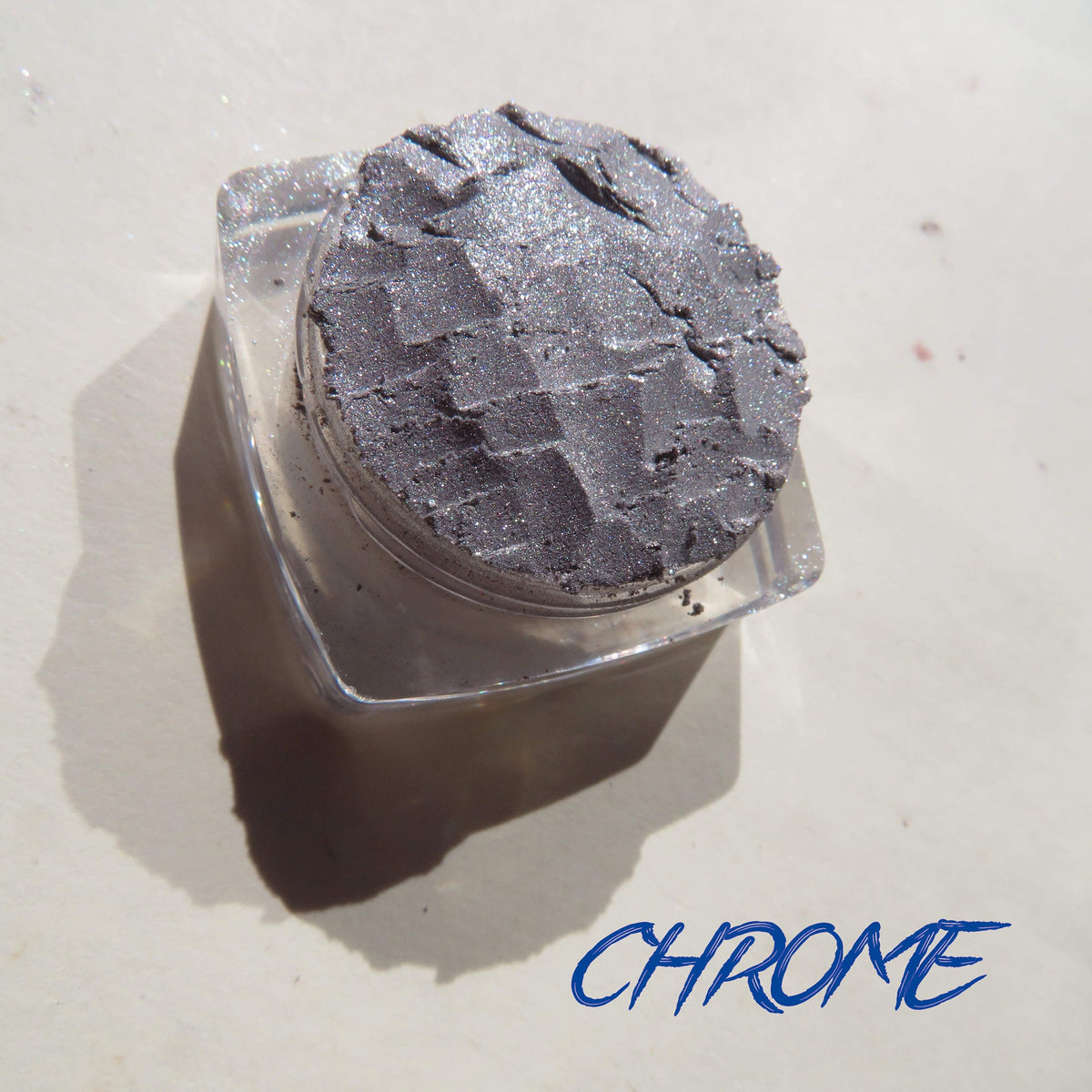 Shimmery silver chrome loose pigment eyeshadow in a small round jar with black lid, vegan and eco-friendly makeup product