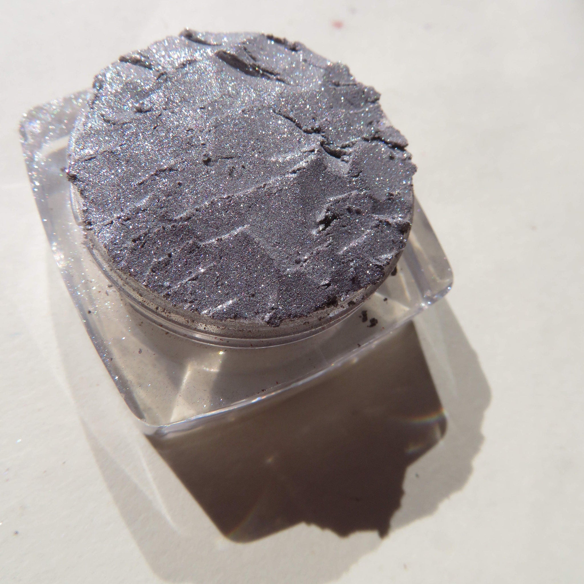 Side view of shimmery silver chrome loose pigment eyeshadow in vegan eco-friendly packaging, showcasing reflective particles