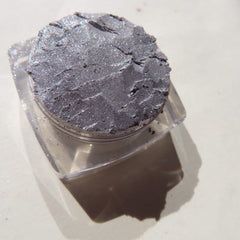 Side view of shimmery silver chrome loose pigment eyeshadow in vegan eco-friendly packaging, showcasing reflective particles