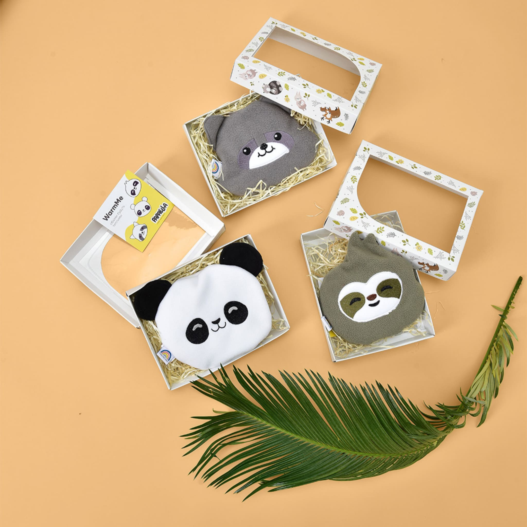 Animal-shaped WarmMe face masks in gray, white, and green with animal faces in gift boxes