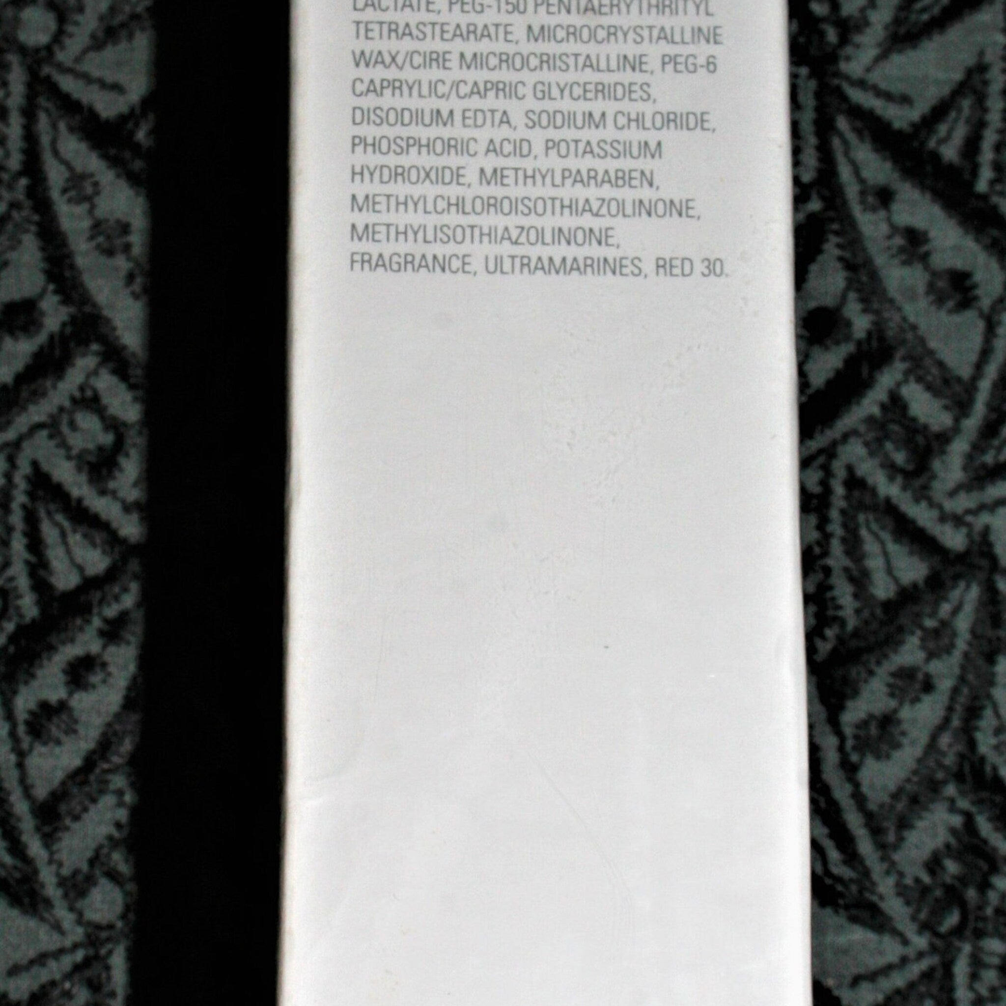 White product ingredient list with black patterned background and black side border