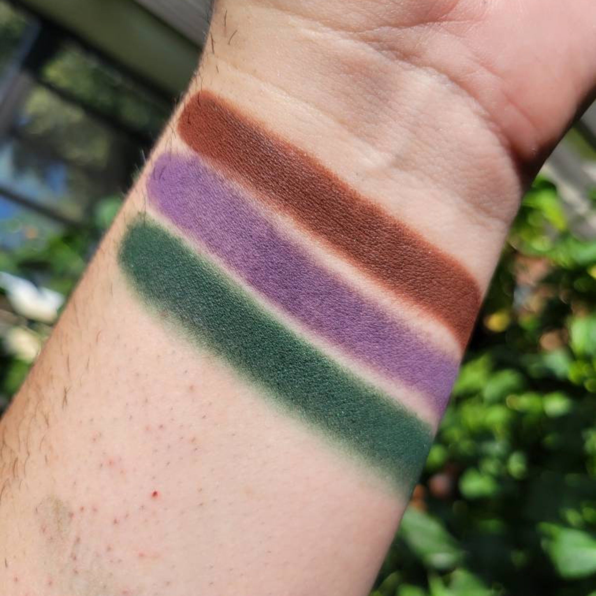 Eyeshadow swatches, green, purple, and brown matte colors on skin for testing