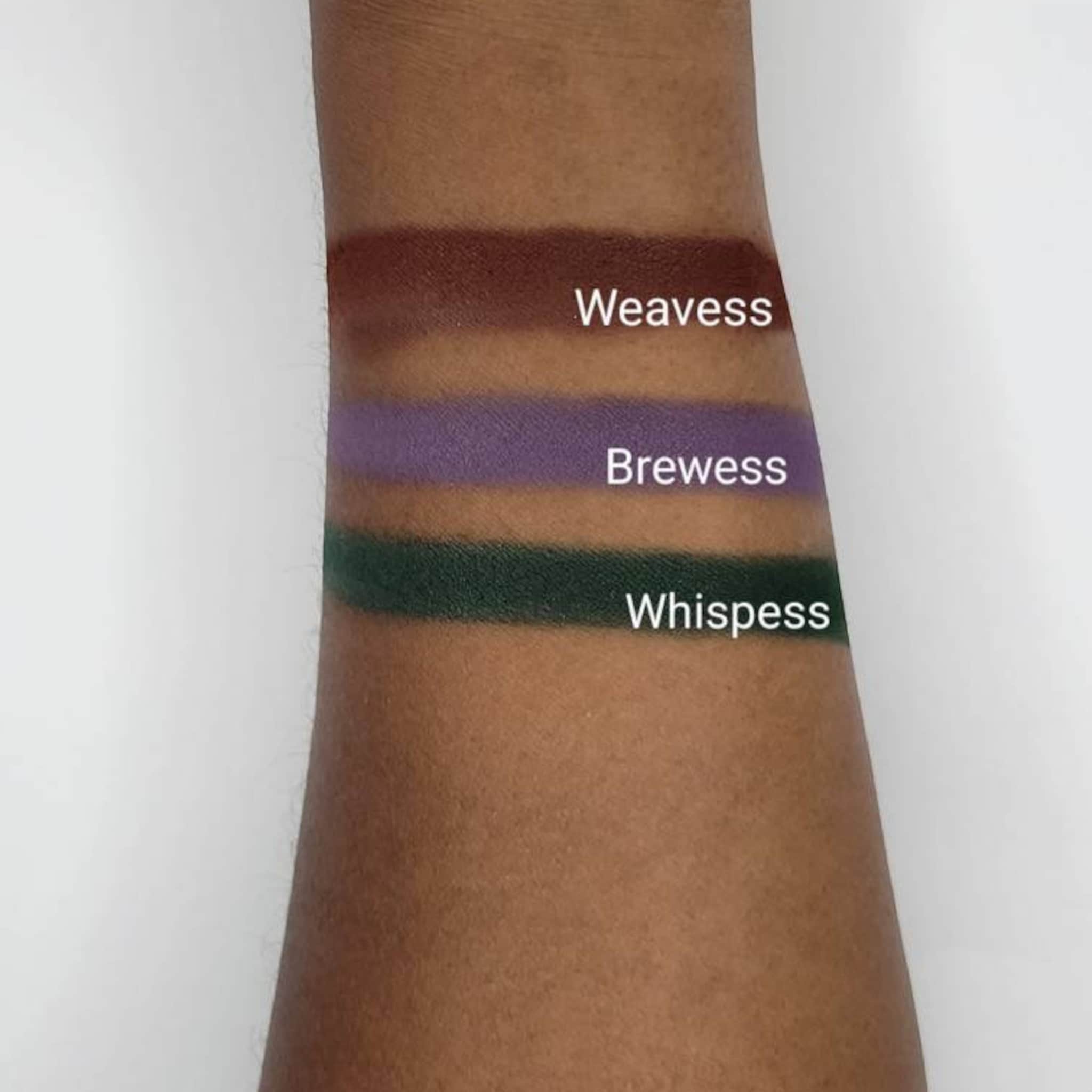 Swatches of brown, purple, and green eyeshadow on arm, with text "Weavess, Brewess, Whispess