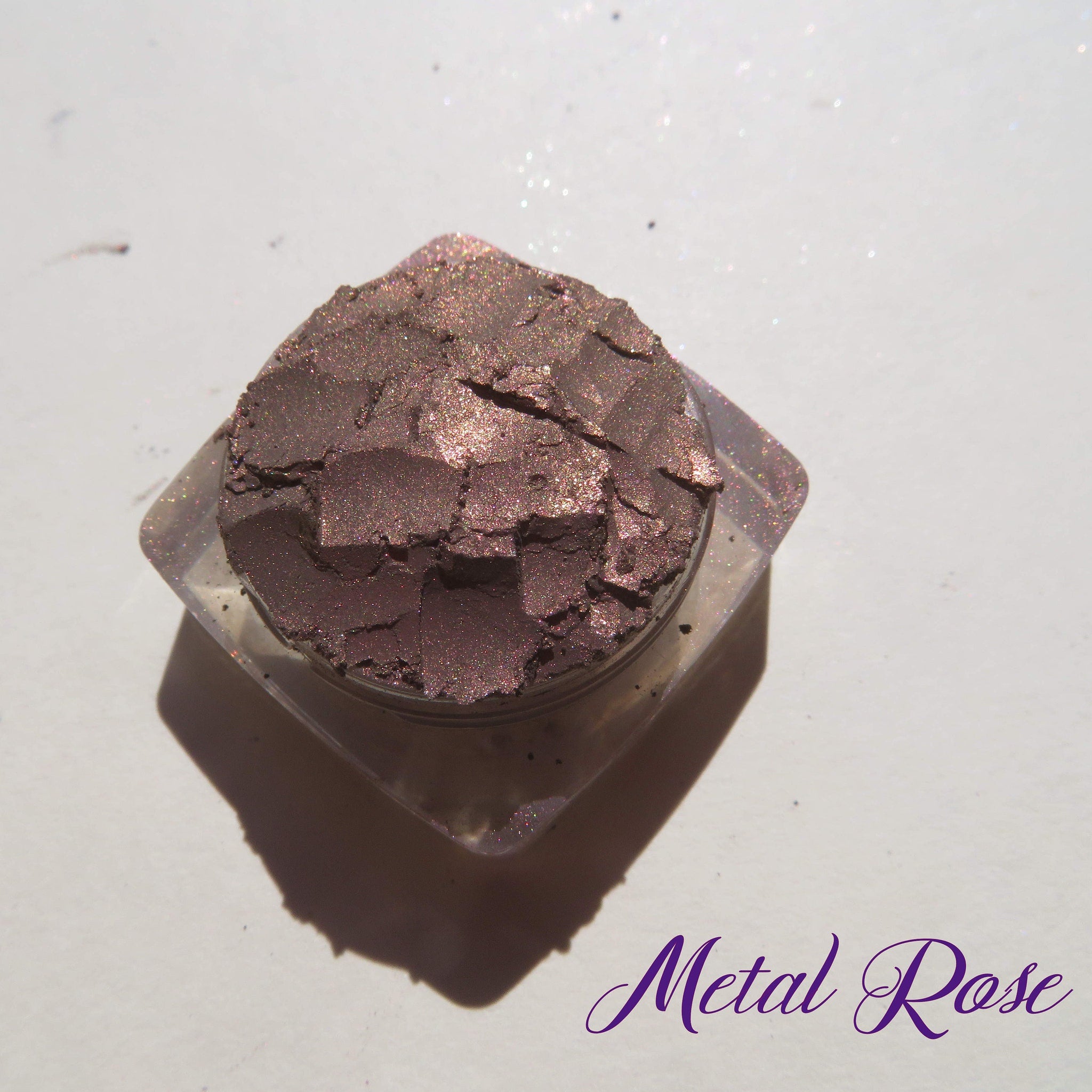 Close-up of loose mineral eyeshadow in dark brown with shimmering rose metal finish, vegan and cruelty-free.