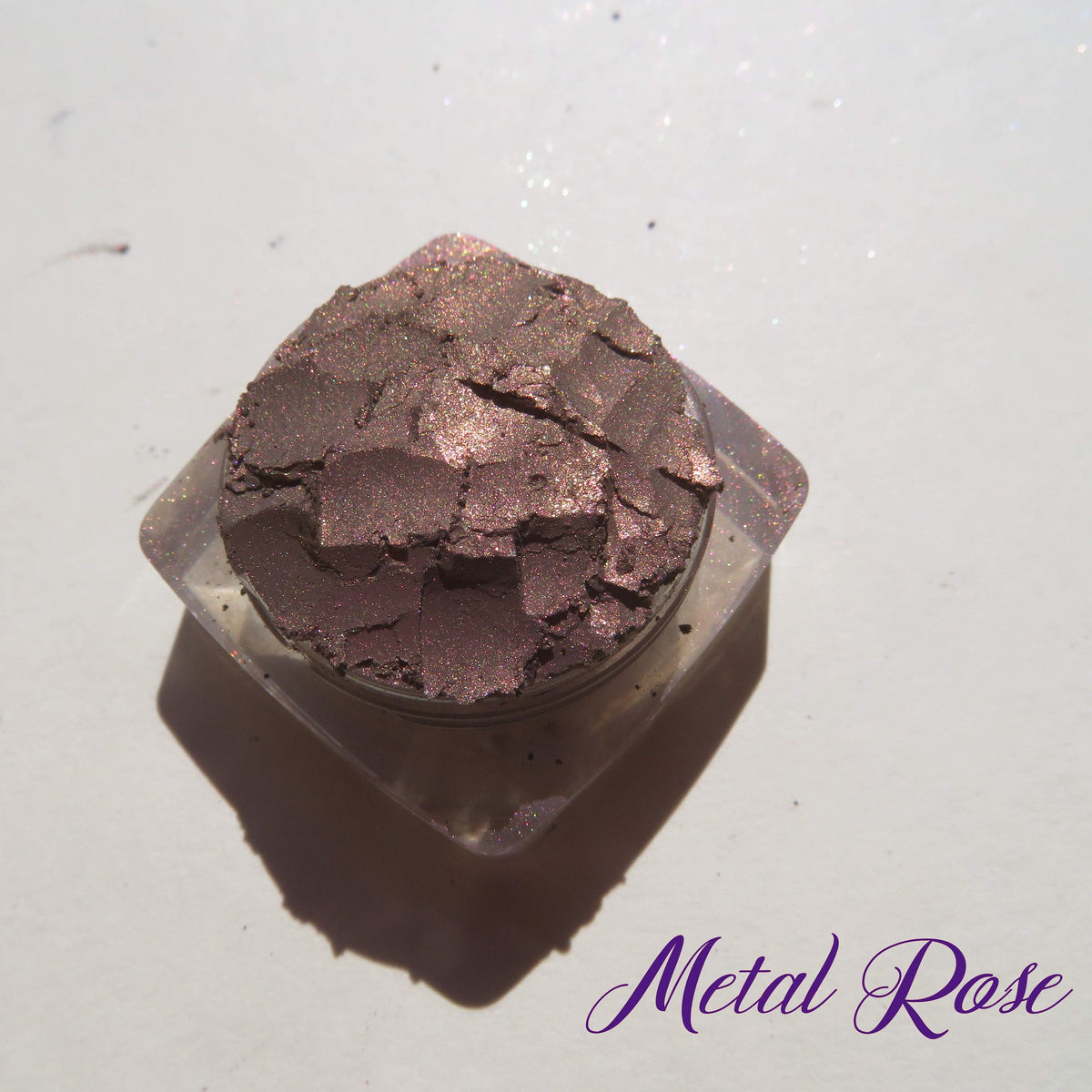 Close-up of loose mineral eyeshadow in dark brown with shimmering rose metal finish, vegan and cruelty-free.