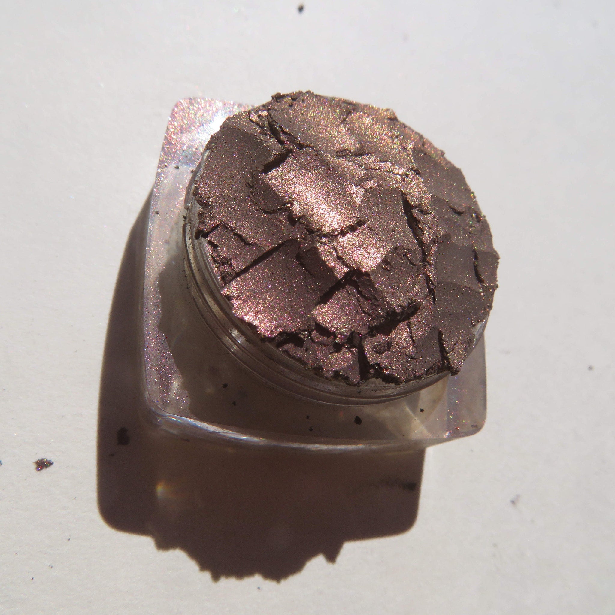 Open compact showing loose mineral eyeshadow in shimmering dark brown with rose metal finish