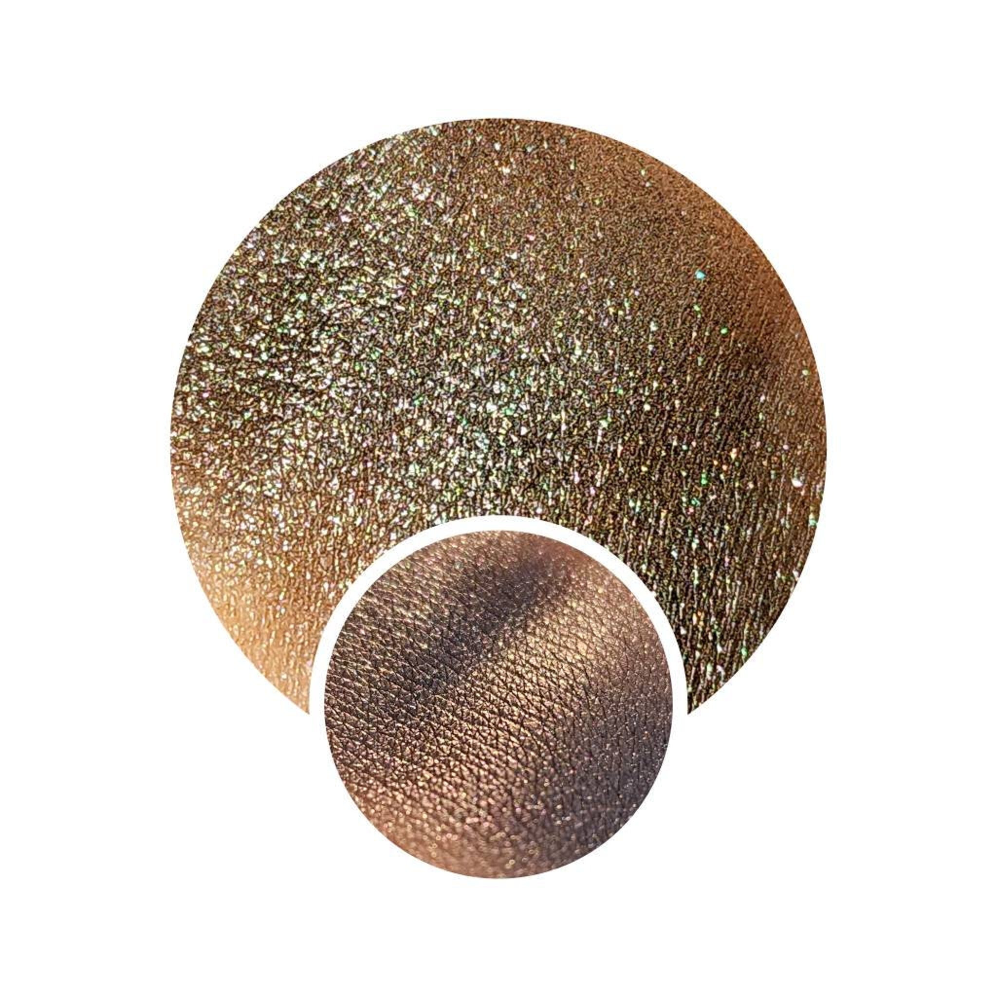 Pressed eyeshadow pan with multichrome grey-to-color shift shimmer in sleek black compact.