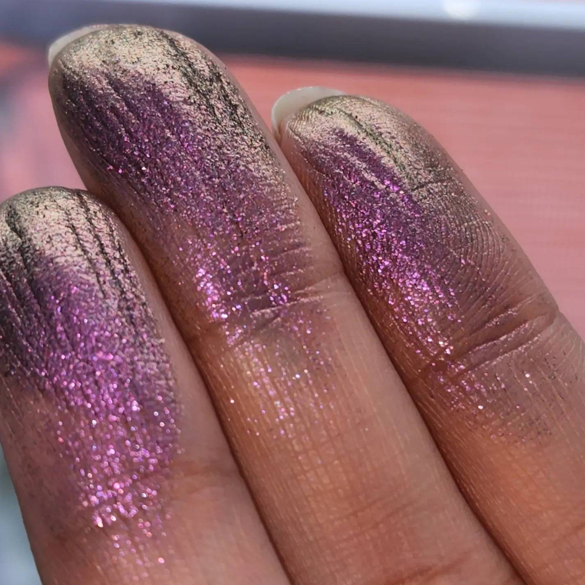 Close-up of pressed purple-olive eyeshadow pan with shimmering chameleon color shift and sparkling trichrome finish