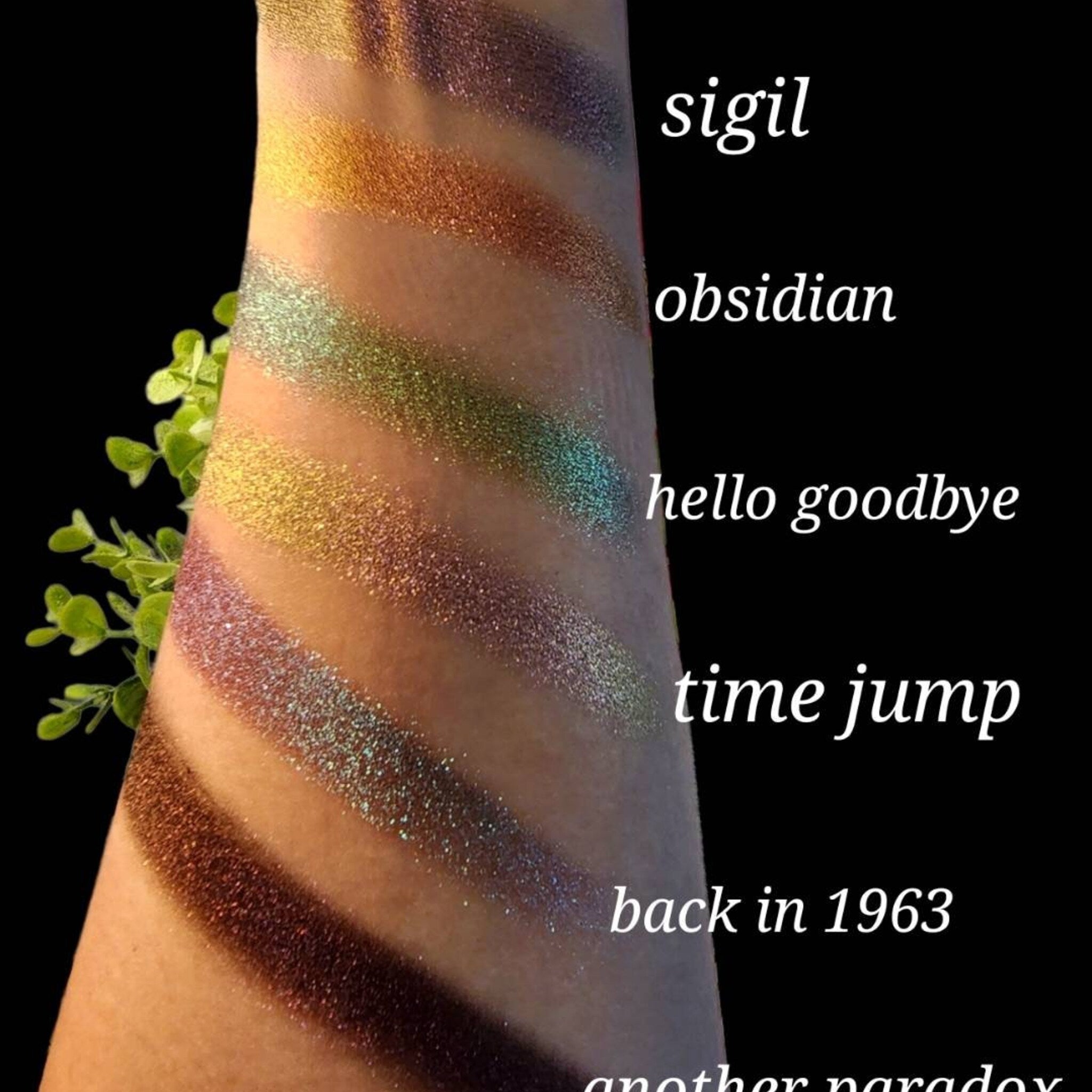 Close-up of pressed trichrome eyeshadow pan showing color shift from green to gold with vegan shimmer particles
