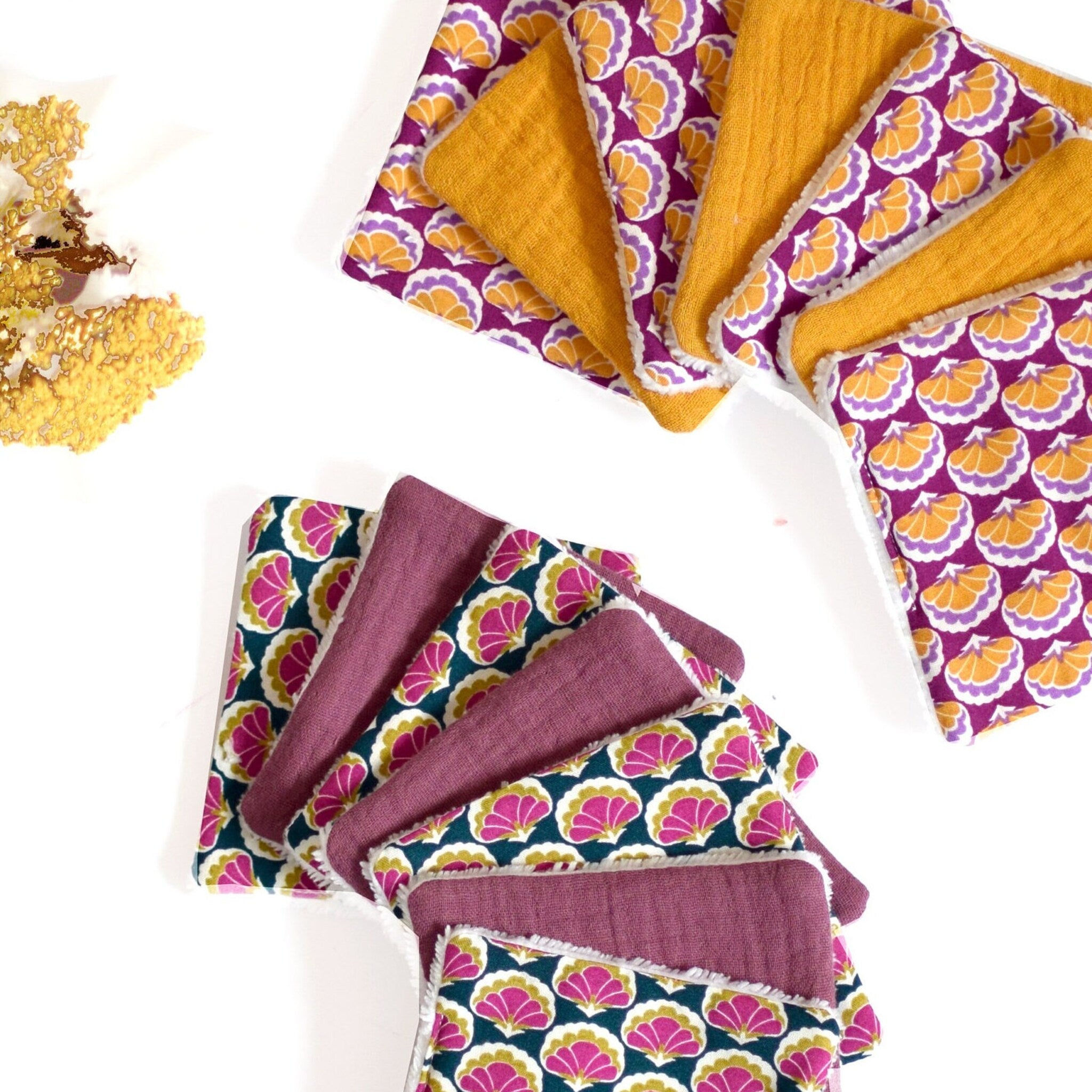 Cloth wipes with floral pattern, solid color, and white trim, stacked on white surface