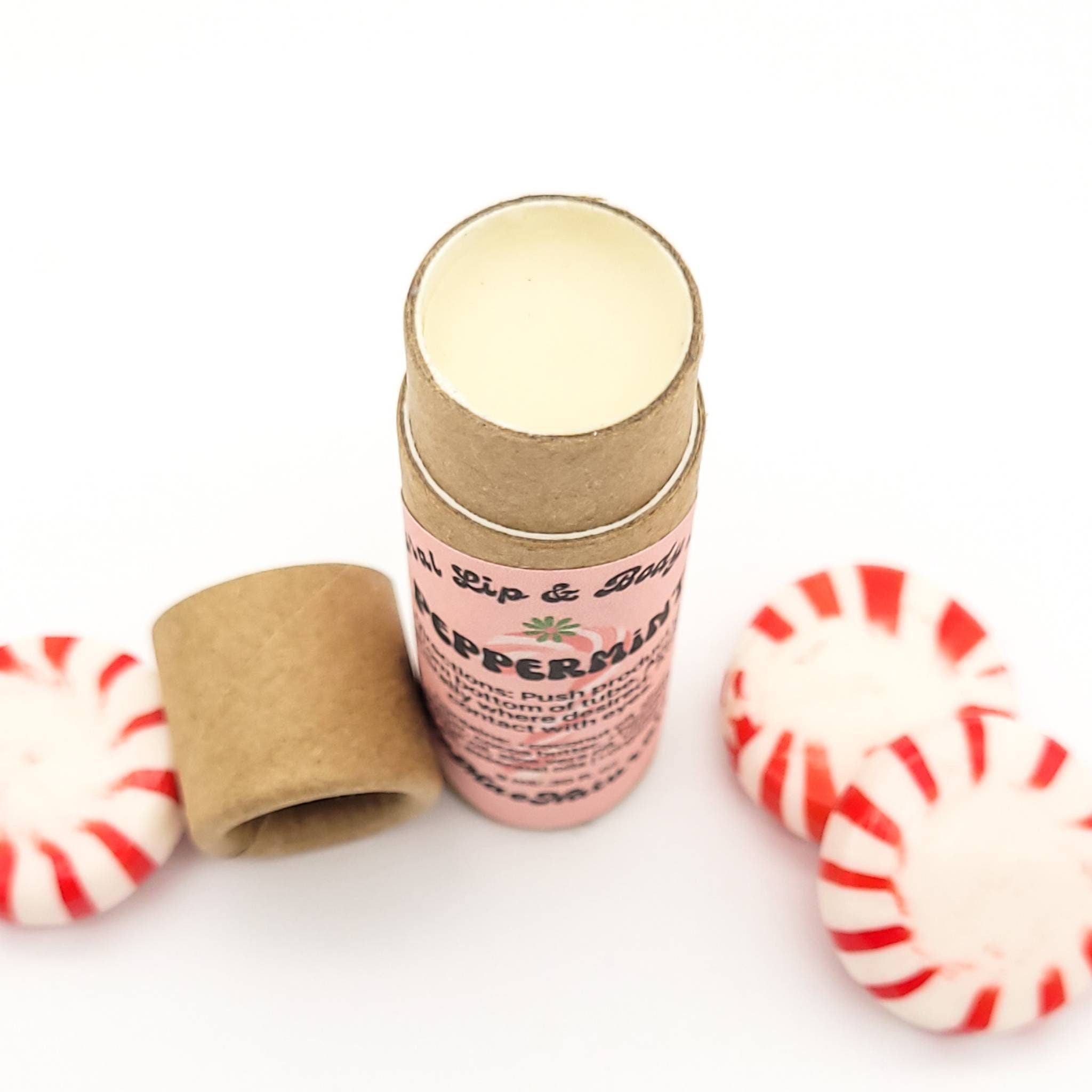 Lip balm tube with pink label, brown cardboard, and peppermint candies with red stripes