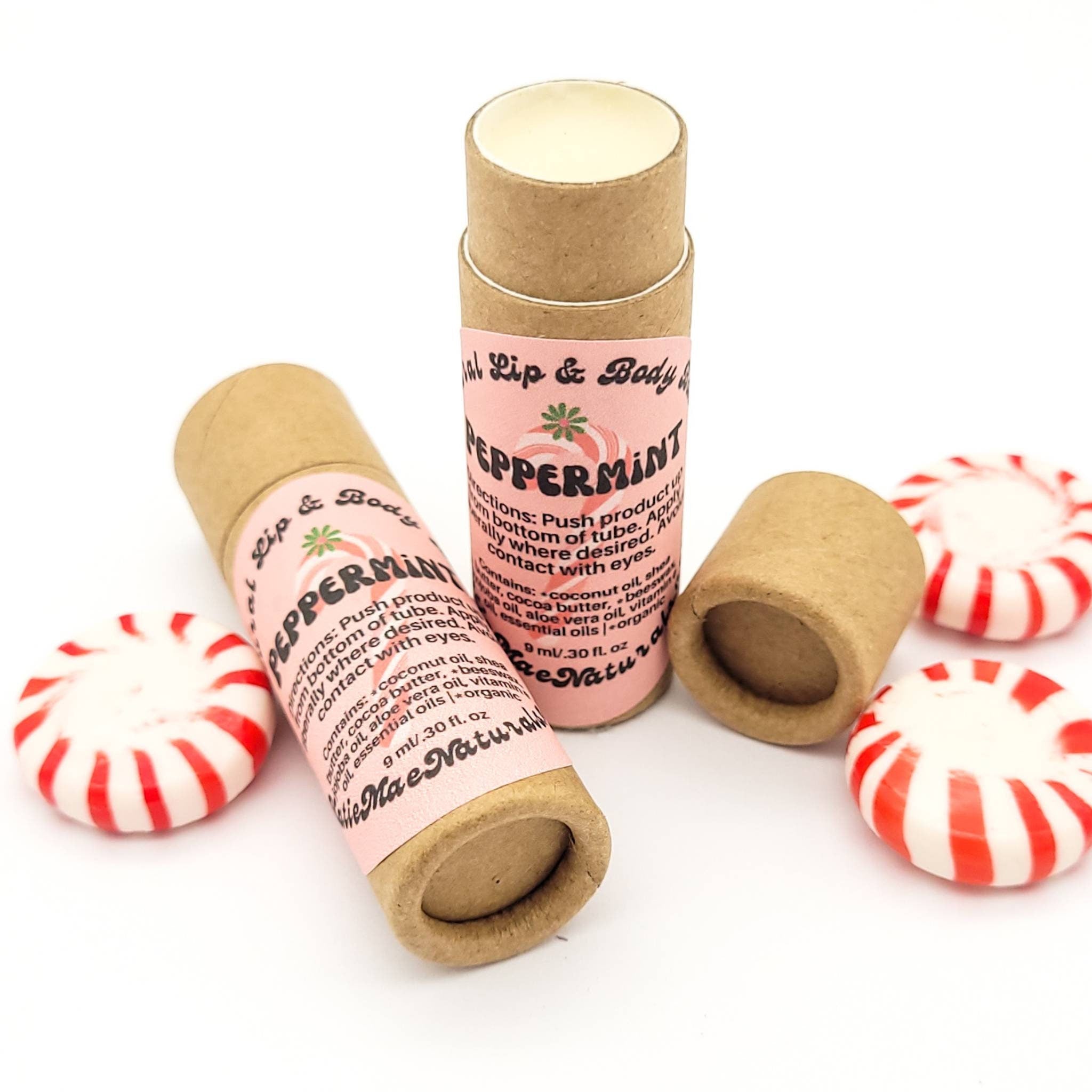 Lip balm tubes with pink label, brown cardboard, and red and white mints beside them
