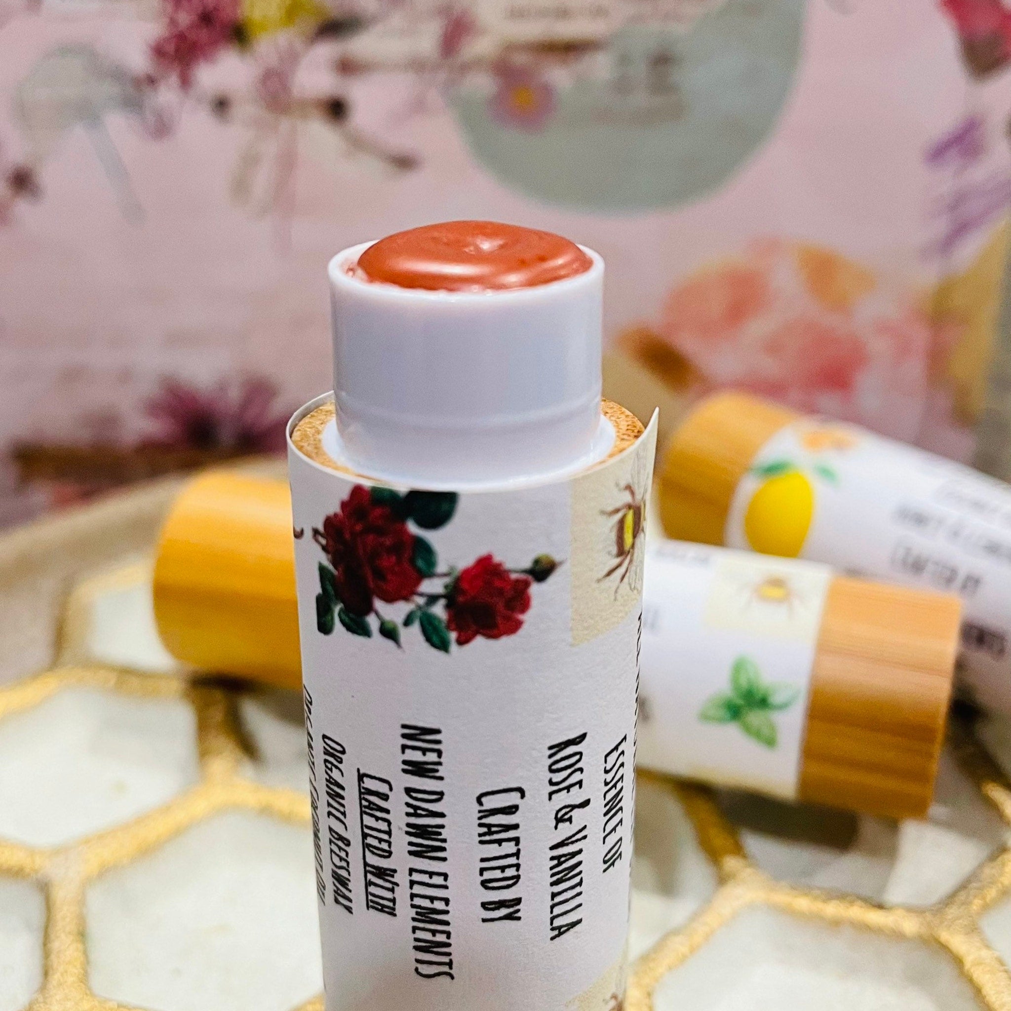 Lip balm with rose and vanilla, white tube with red rose graphic, New Dawn Elements brand visible