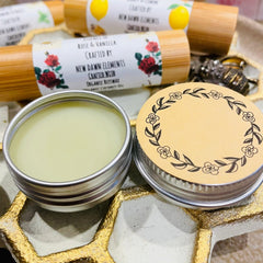 Lip balm tins with light green balm, floral design lid, and bamboo tubes with New Dawn Elements labels