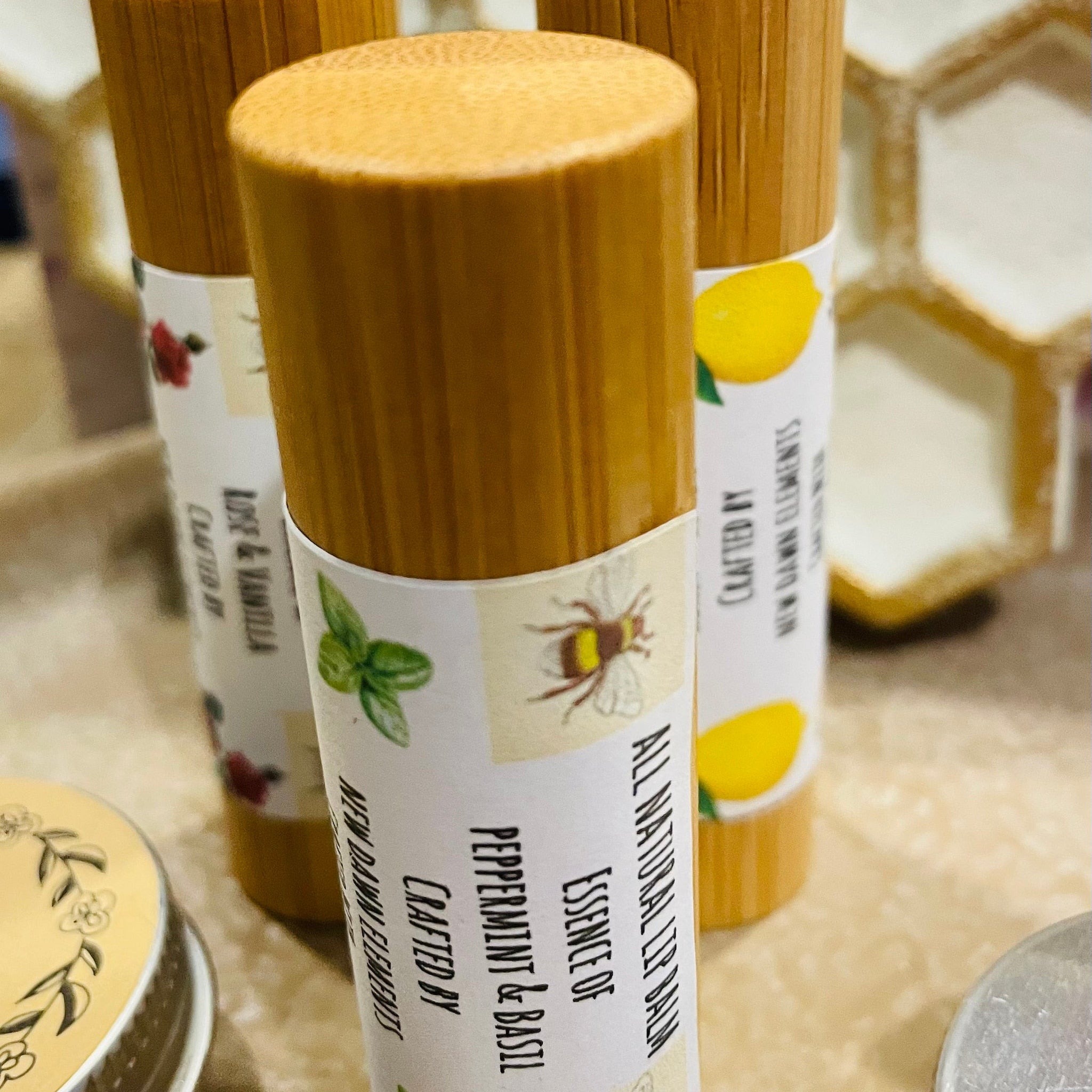 Lip balm tubes with wooden caps, white labels, and botanical illustrations by New Dawn Elements