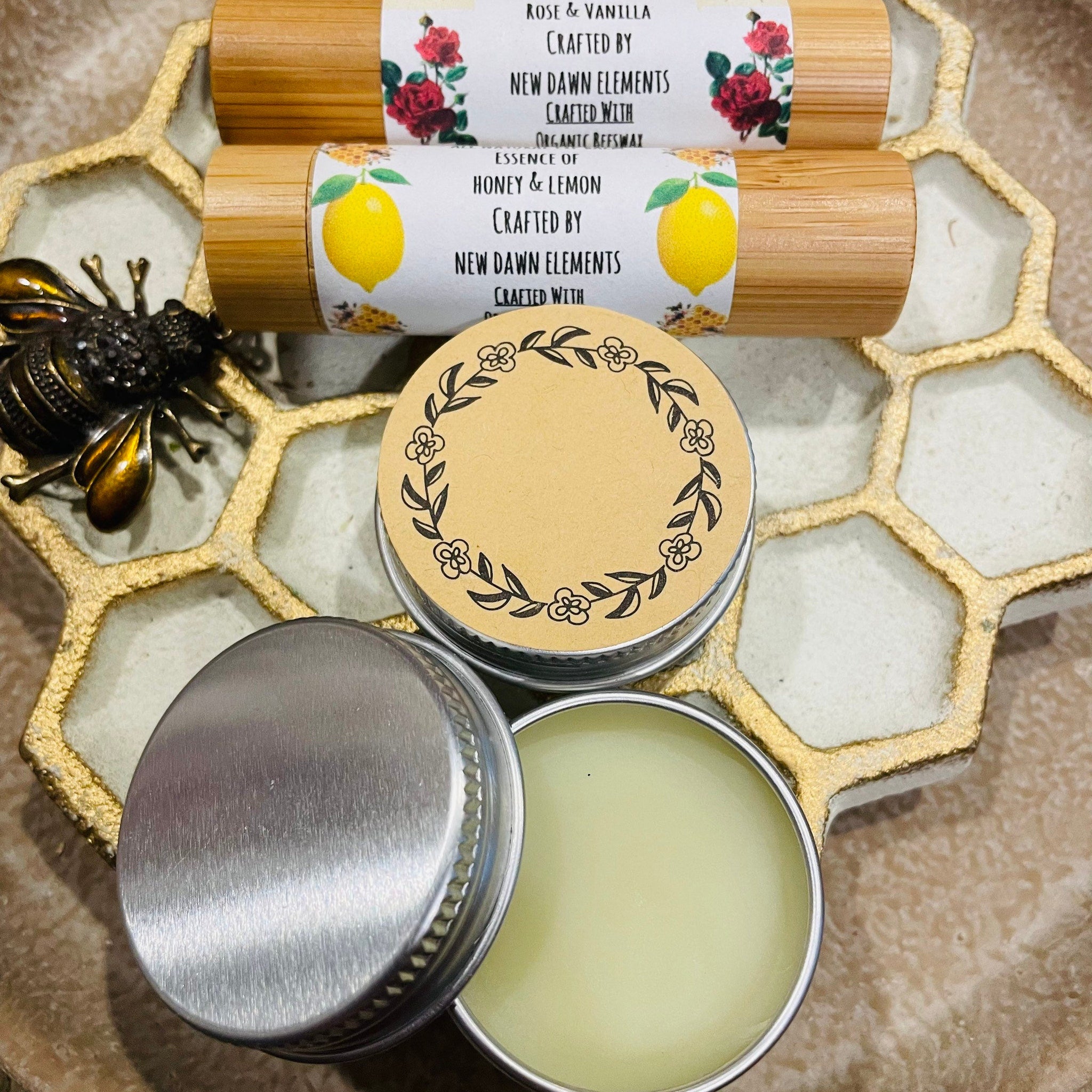 Lip balm tubes with floral labels, bamboo material, and New Dawn Elements text