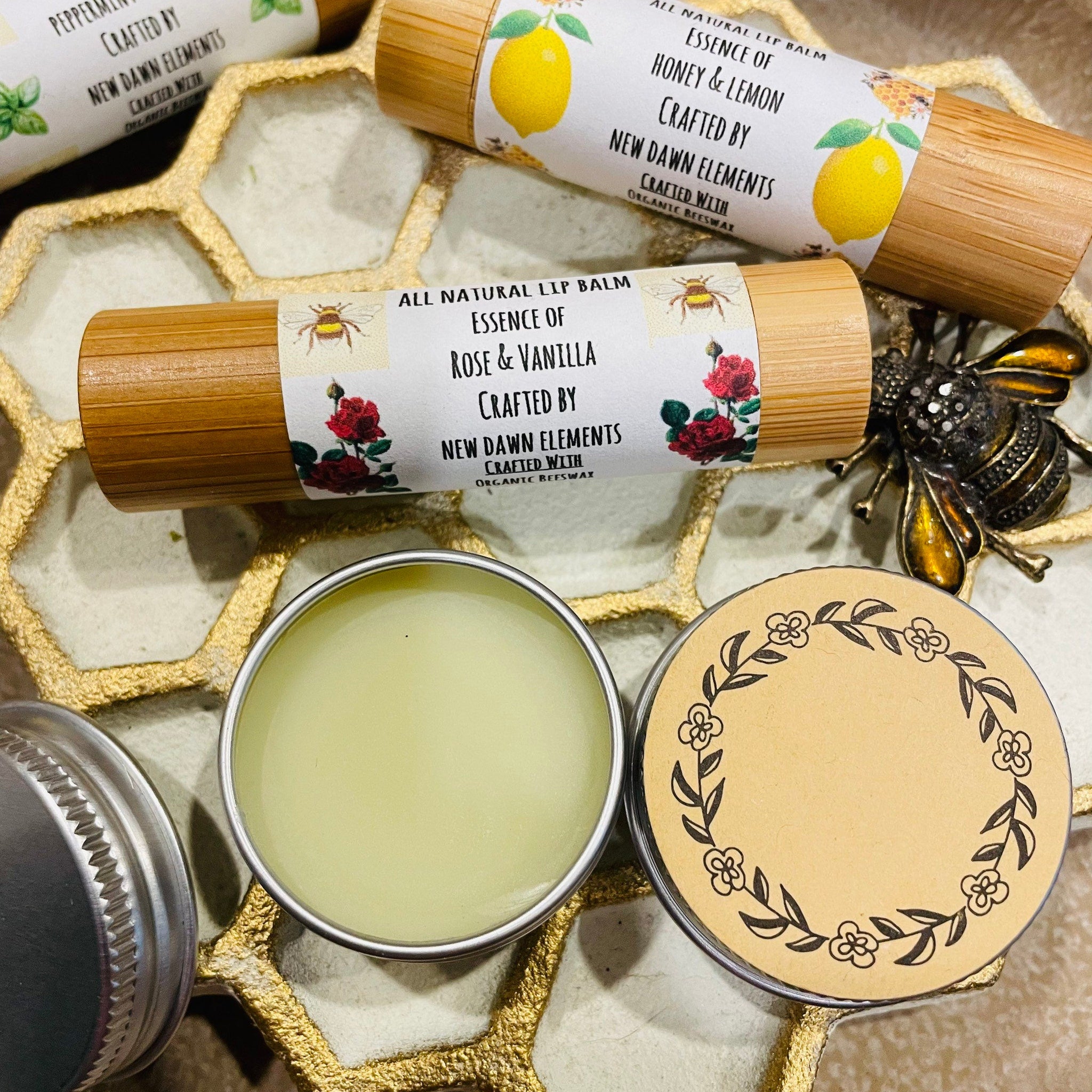 Lip balm tubes with bamboo casing, white labels, and New Dawn Elements text, displayed with other products