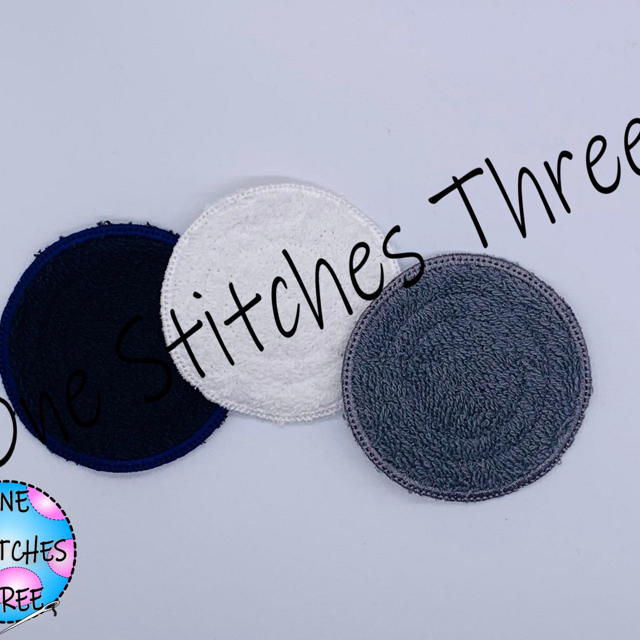 Round fabric pads in navy, white, and gray with One Stitches Three text