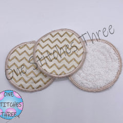 Reusable facial rounds with gold chevron pattern and One Stitches Three branding