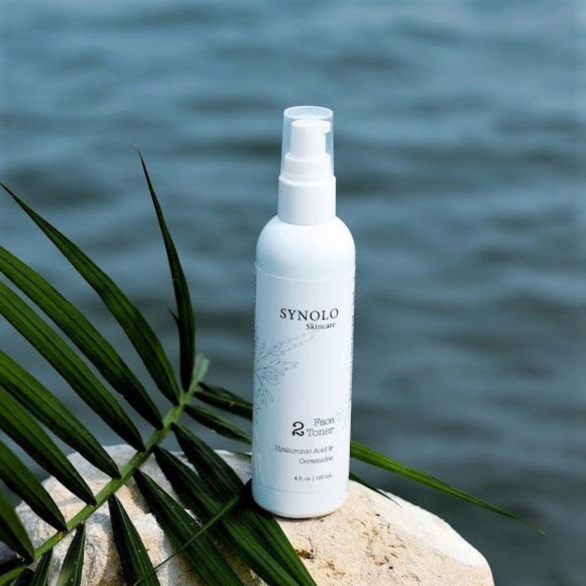Toner bottle white with clear cap, Synolo brand on a rock with green leaves