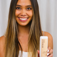 Skincare product held by woman with long brown hair, white bottle with Synolo Skincare label
