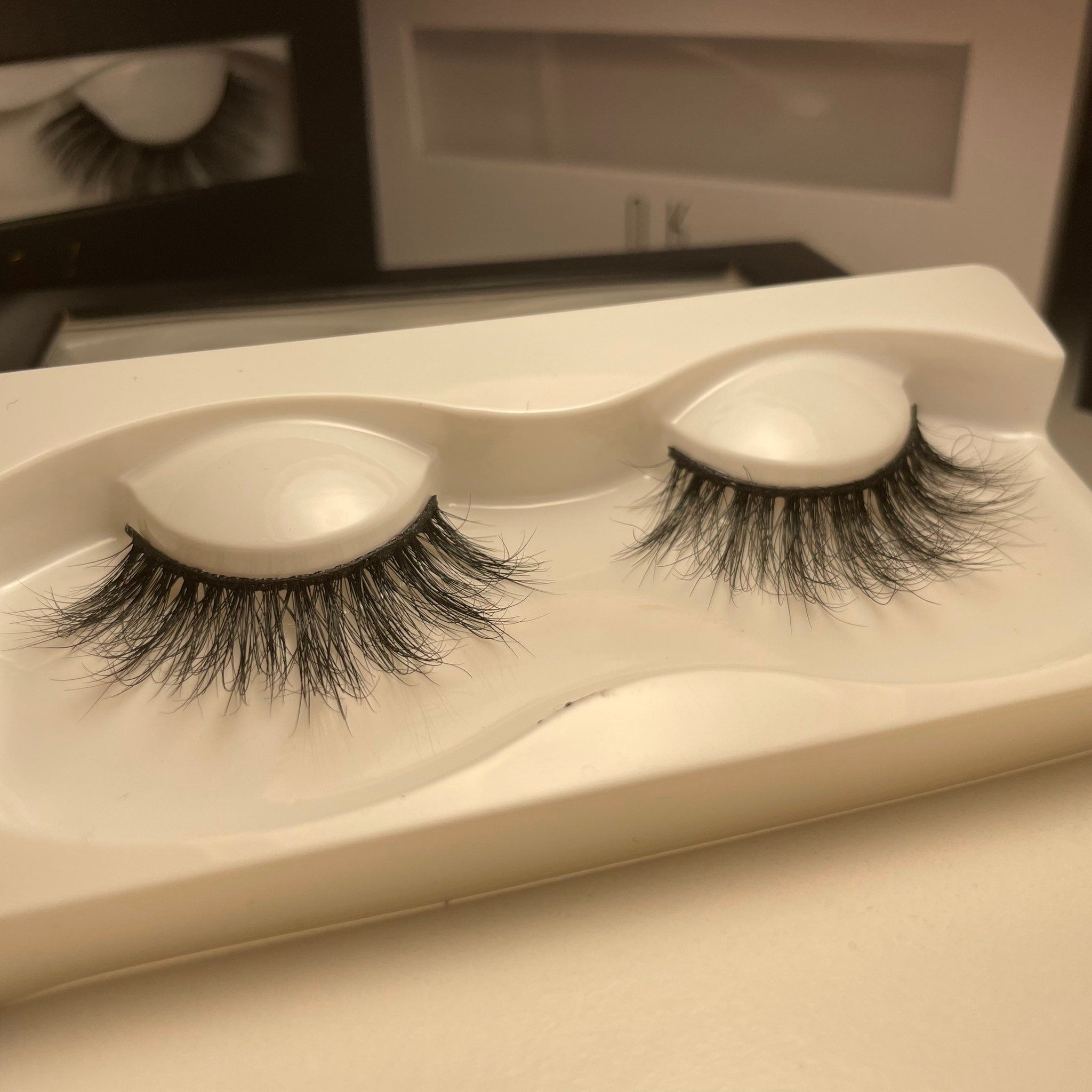 False eyelashes with black synthetic fibers, in a white plastic tray, for makeup application