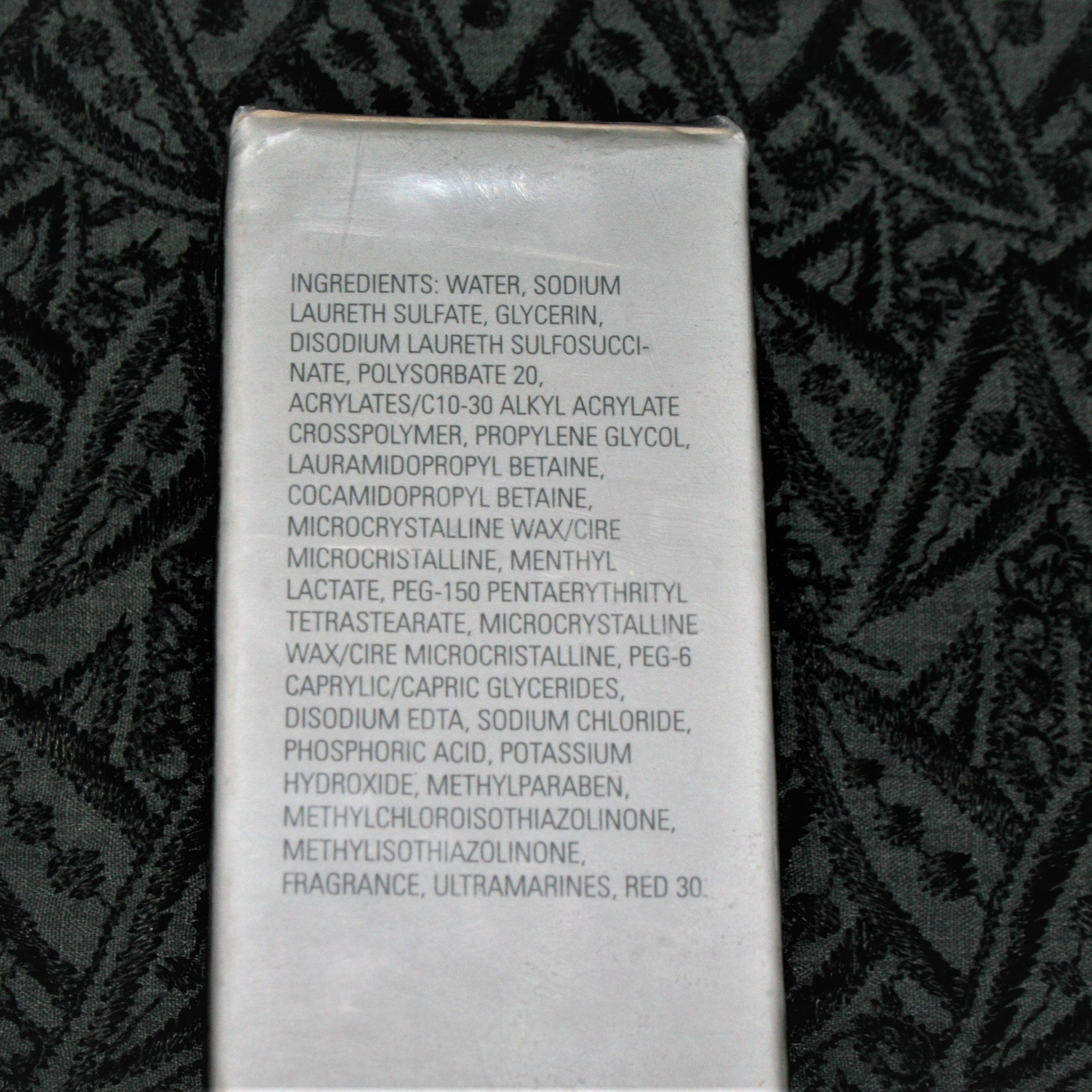 Ingredients list on white rectangular label, with black text, against a dark patterned background