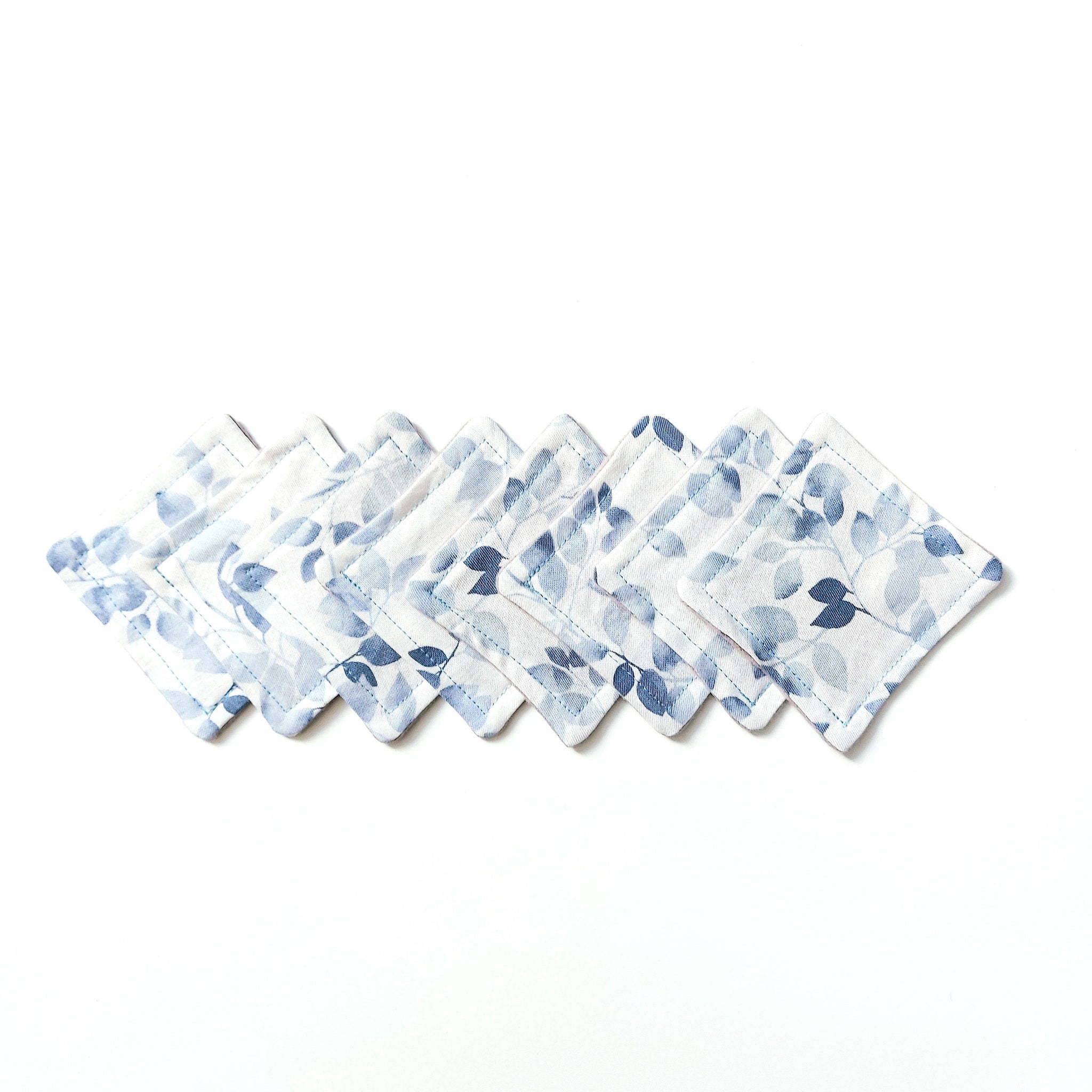 Coasters with blue floral pattern on white fabric, stitched edges, arranged in a row