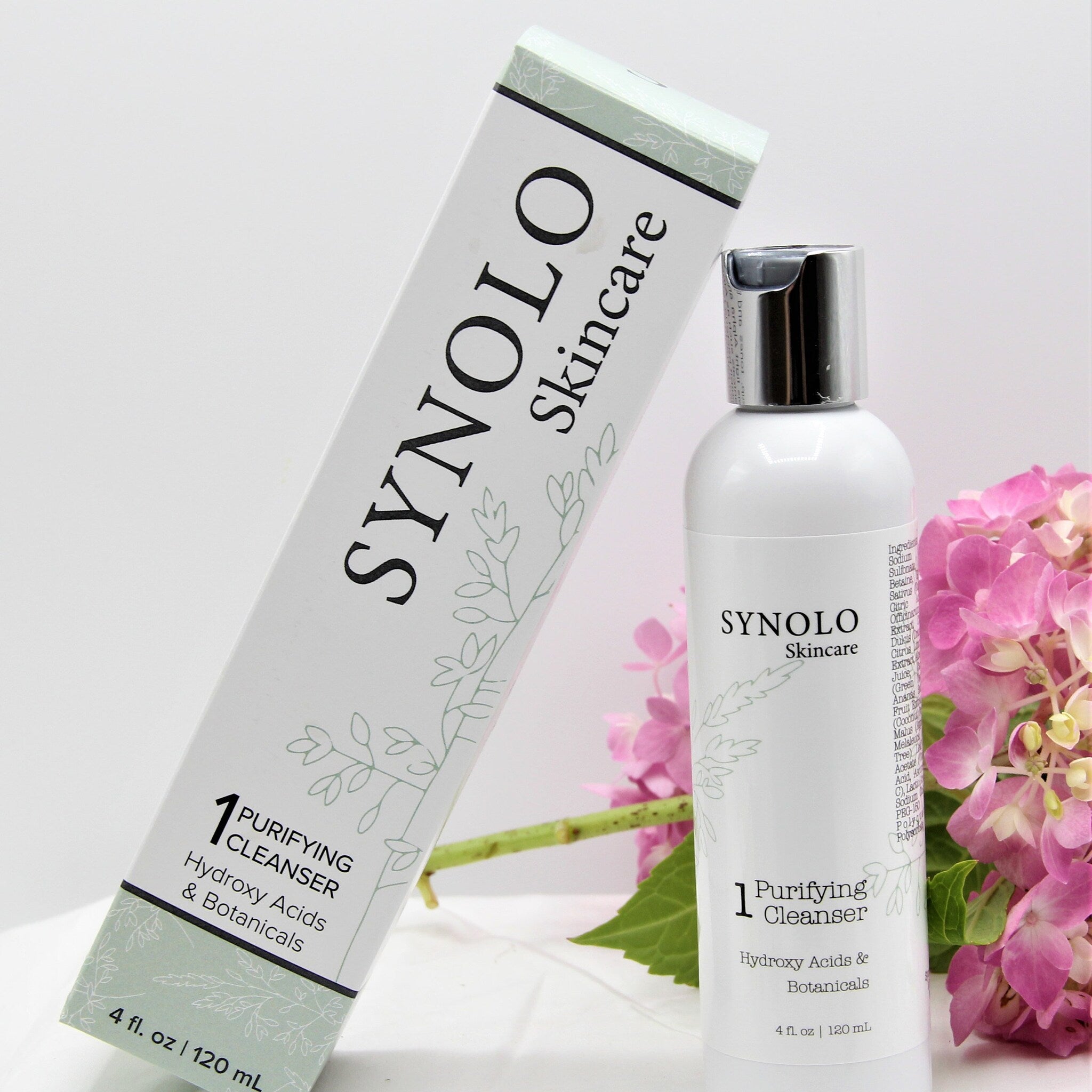 Purifying cleanser bottle and box, white with black text, SYNOLO Skincare brand, floral pattern