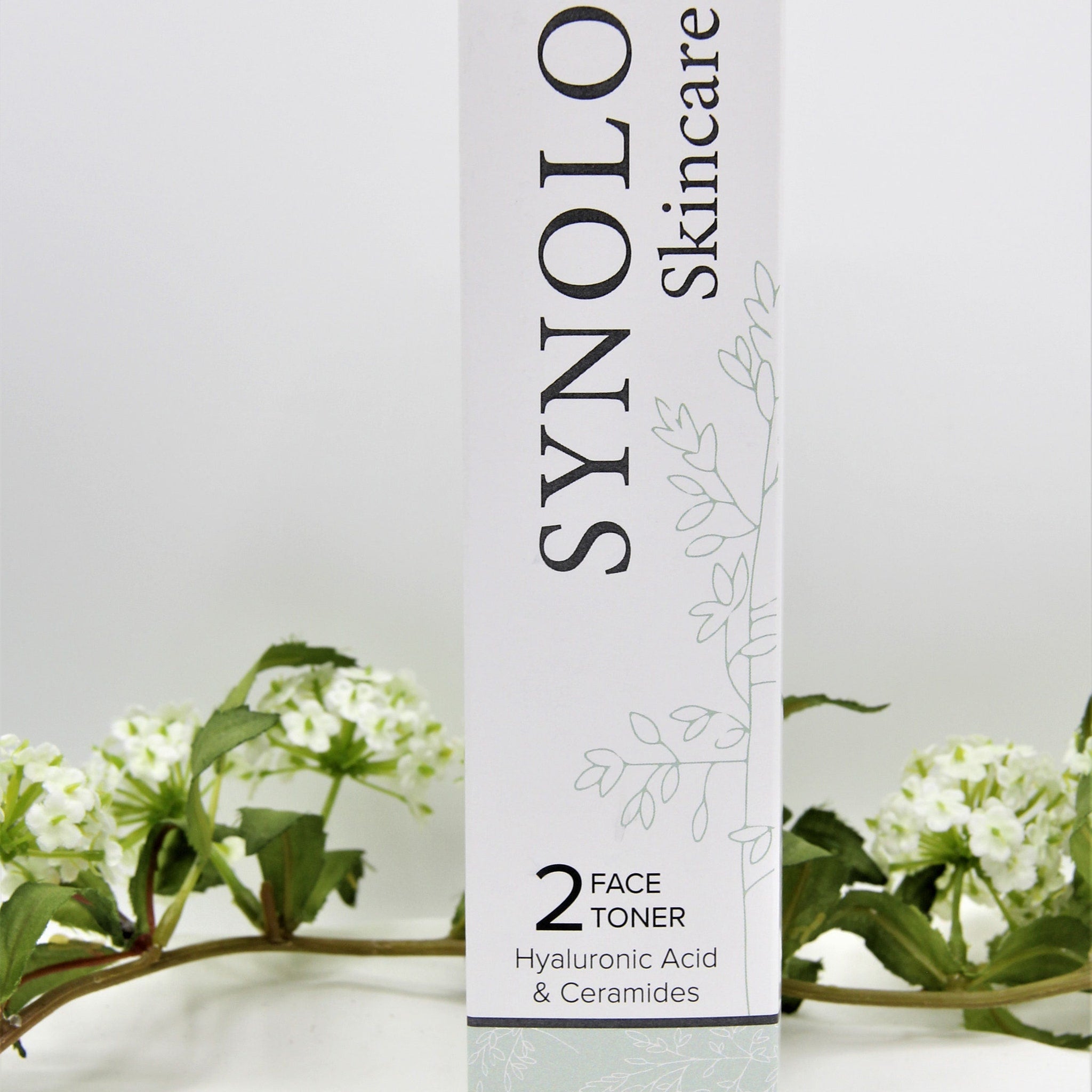 Face toner bottle with white and black text, light green floral pattern, and brand name SYNOLO Skincare