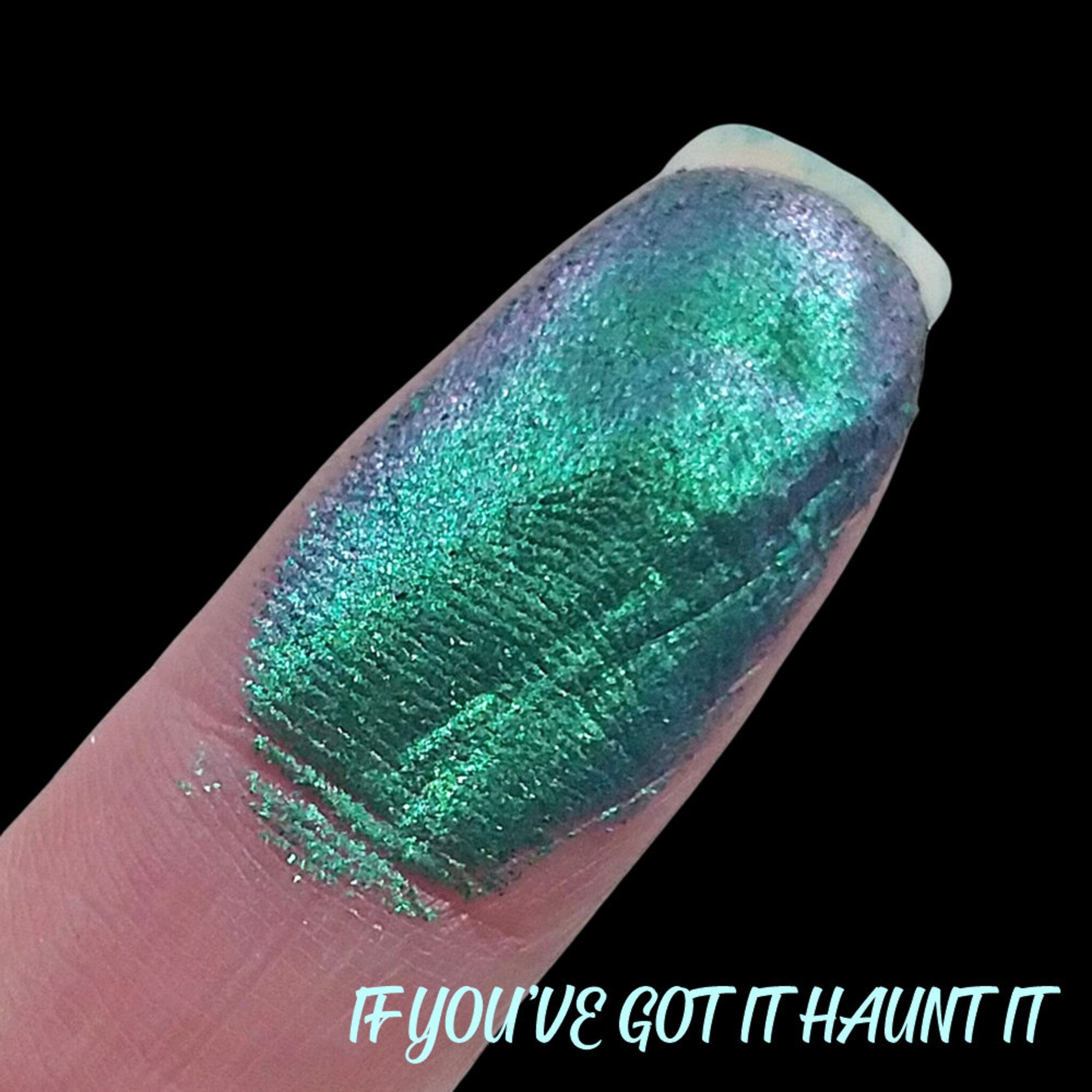 Close-up of duochrome eyeshadow pan showing shifting violet and emerald green shimmer