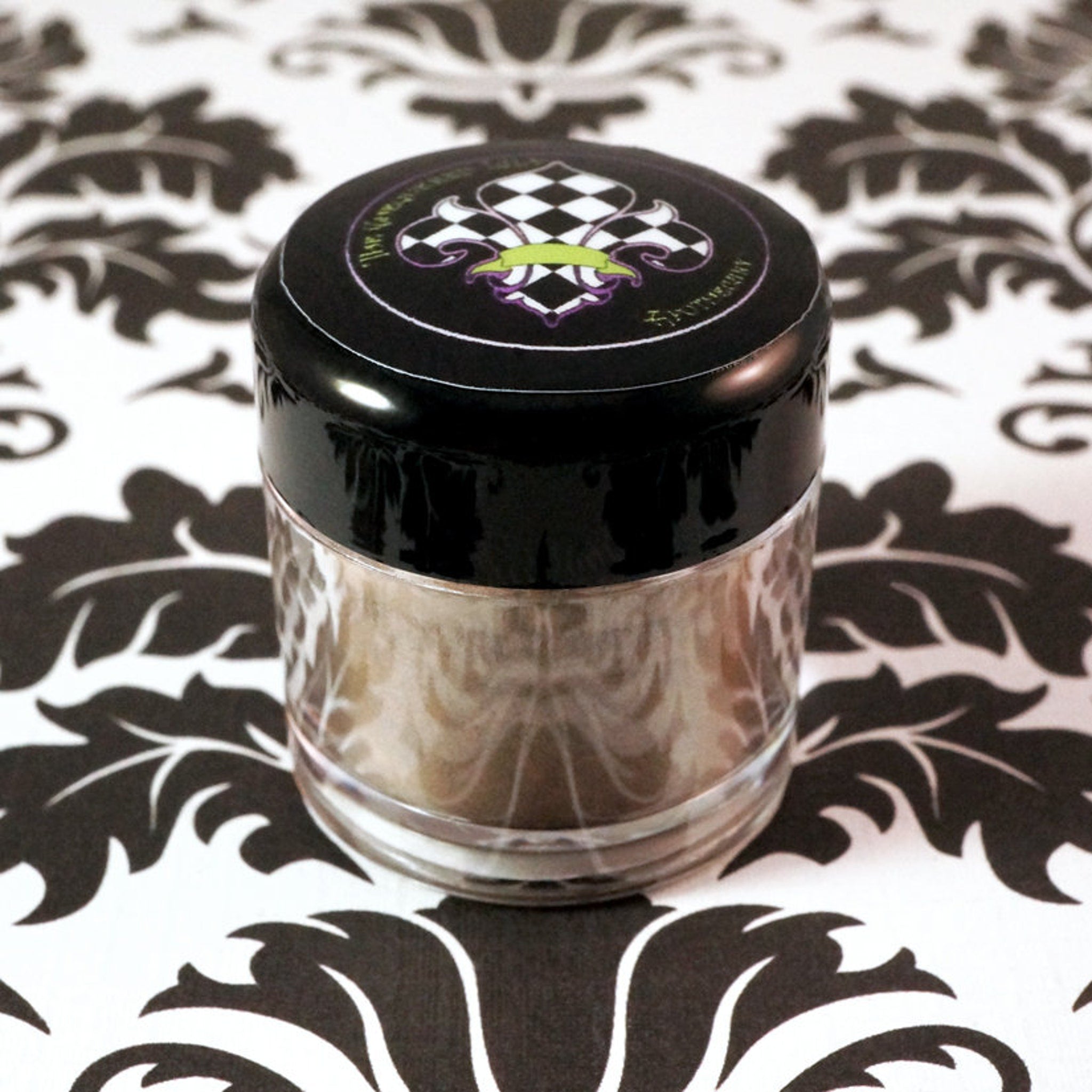 Loose mineral eyeshadow in neutral taupe beige with gold and green shimmer, spilled on marble surface for texture display