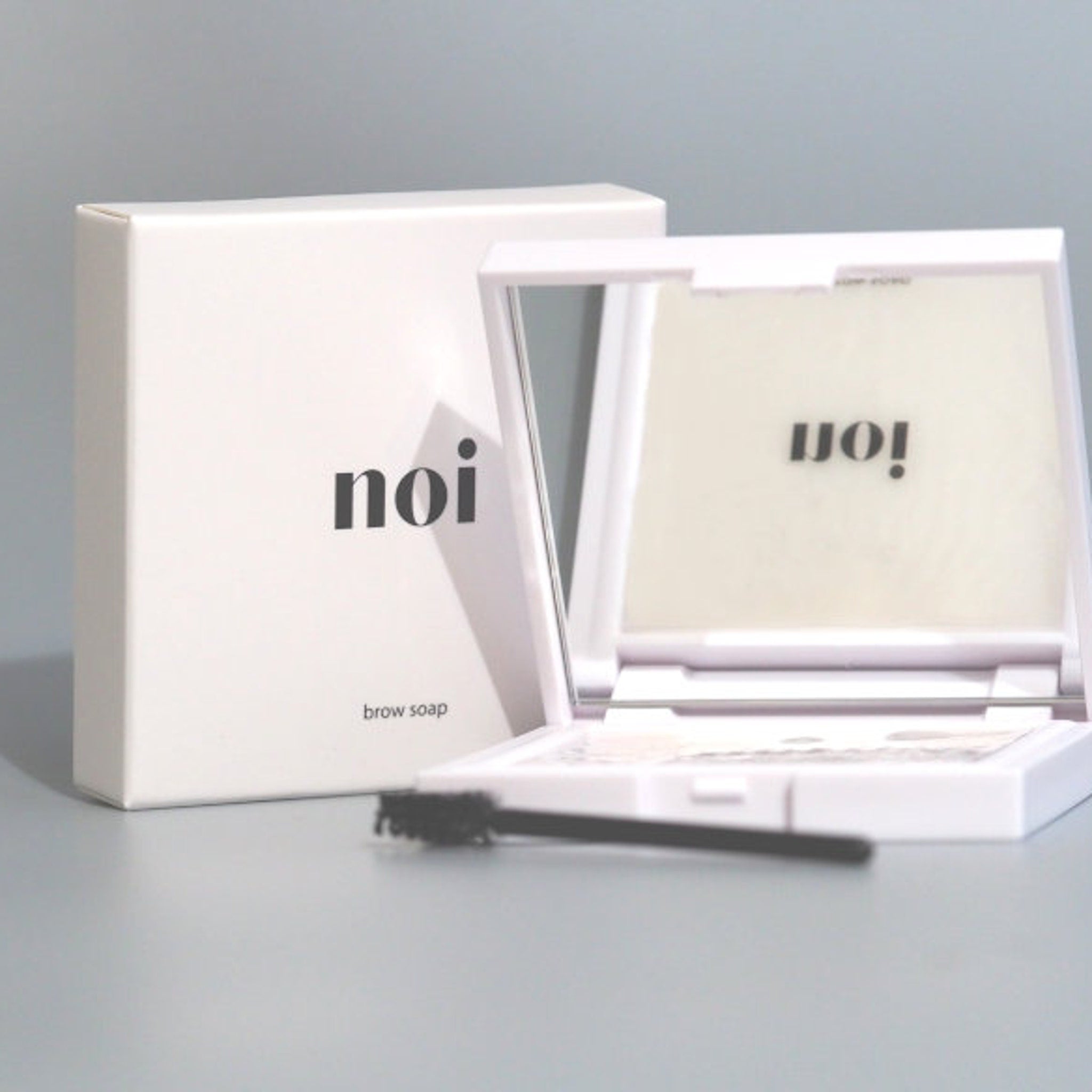 Brow soap kit with white box and compact, black applicator, and "noi" branding visible