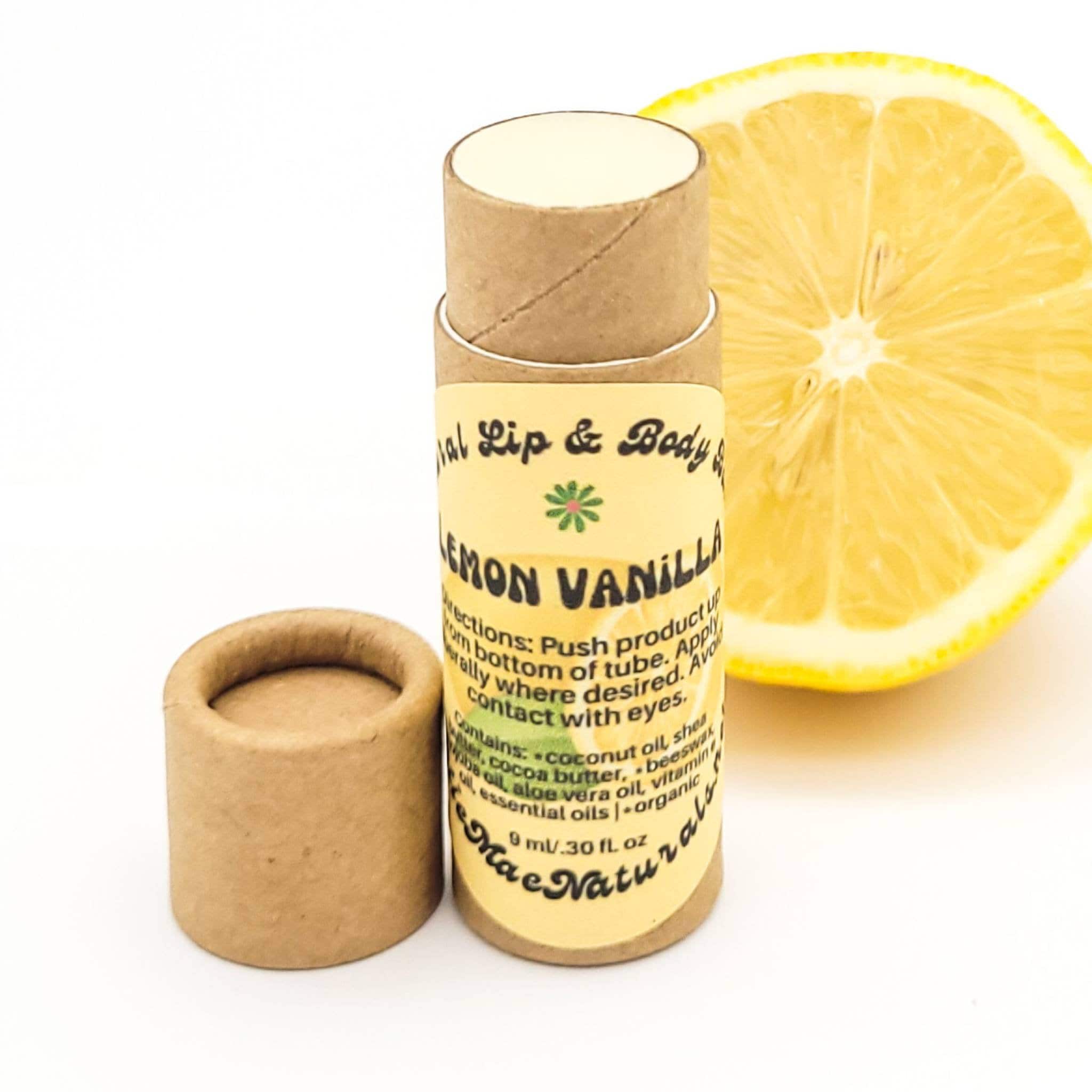 Lip balm tube with brown cardboard, yellow label, and a lemon slice next to it. Mae Naturals brand.