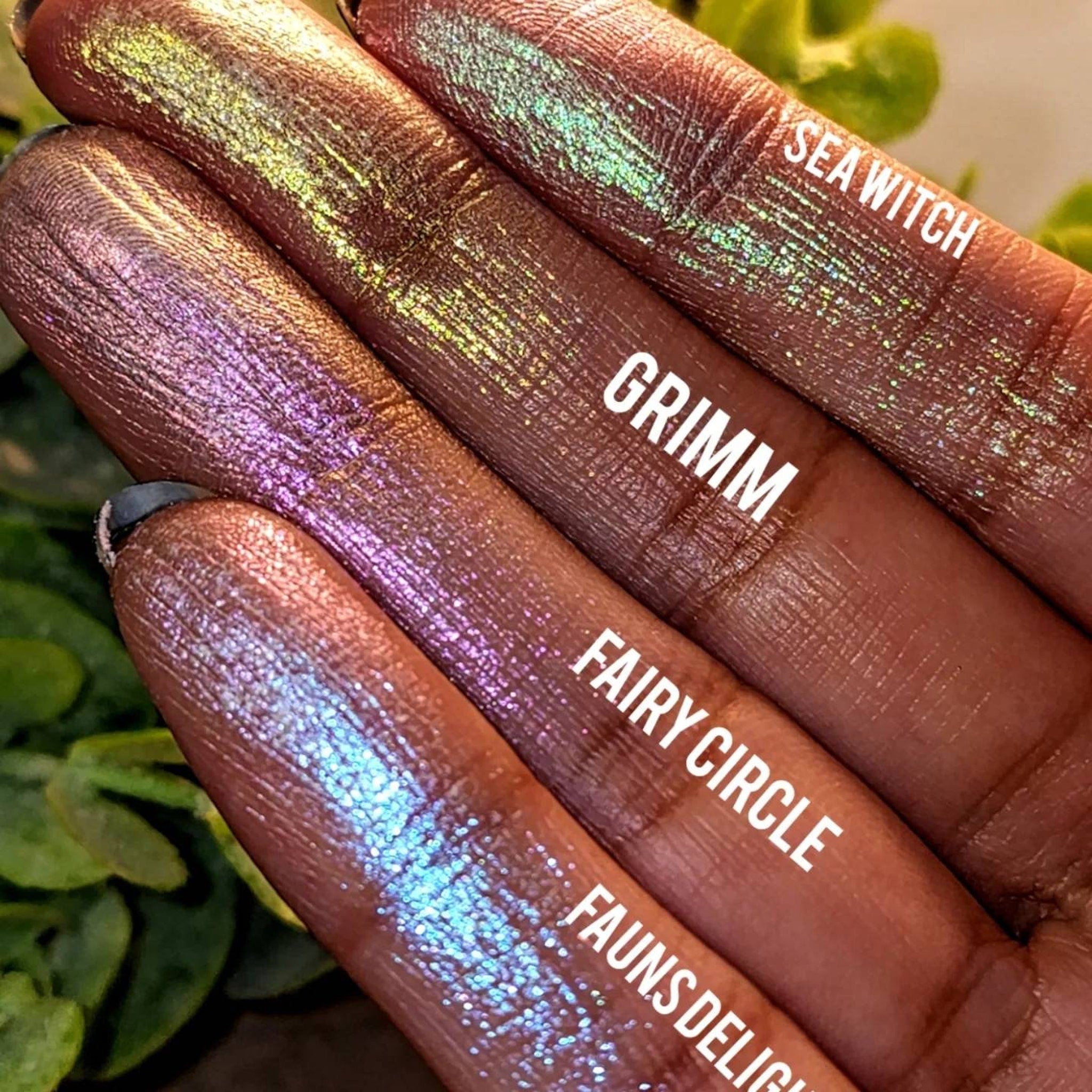 Side view of iridescent green and pink pressed eyeshadow pan with duochrome shimmer in compact case