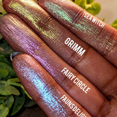 Side view of iridescent green and pink pressed eyeshadow pan with duochrome shimmer in compact case